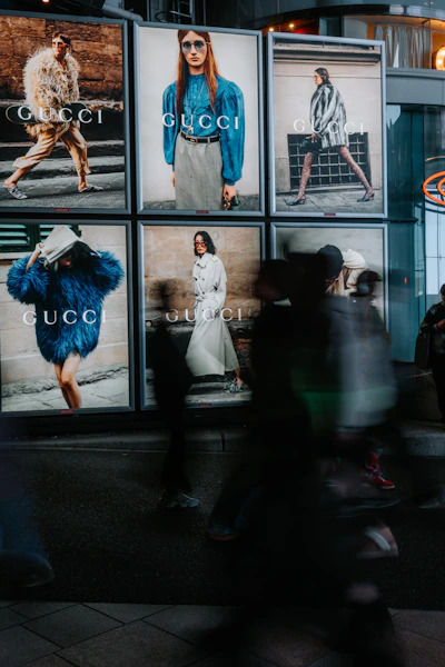People walk past gucci advertisements at night.
