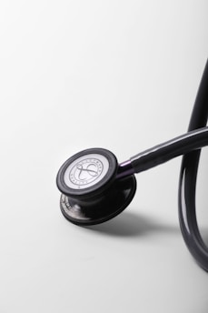 A black stethoscope rests on a white surface