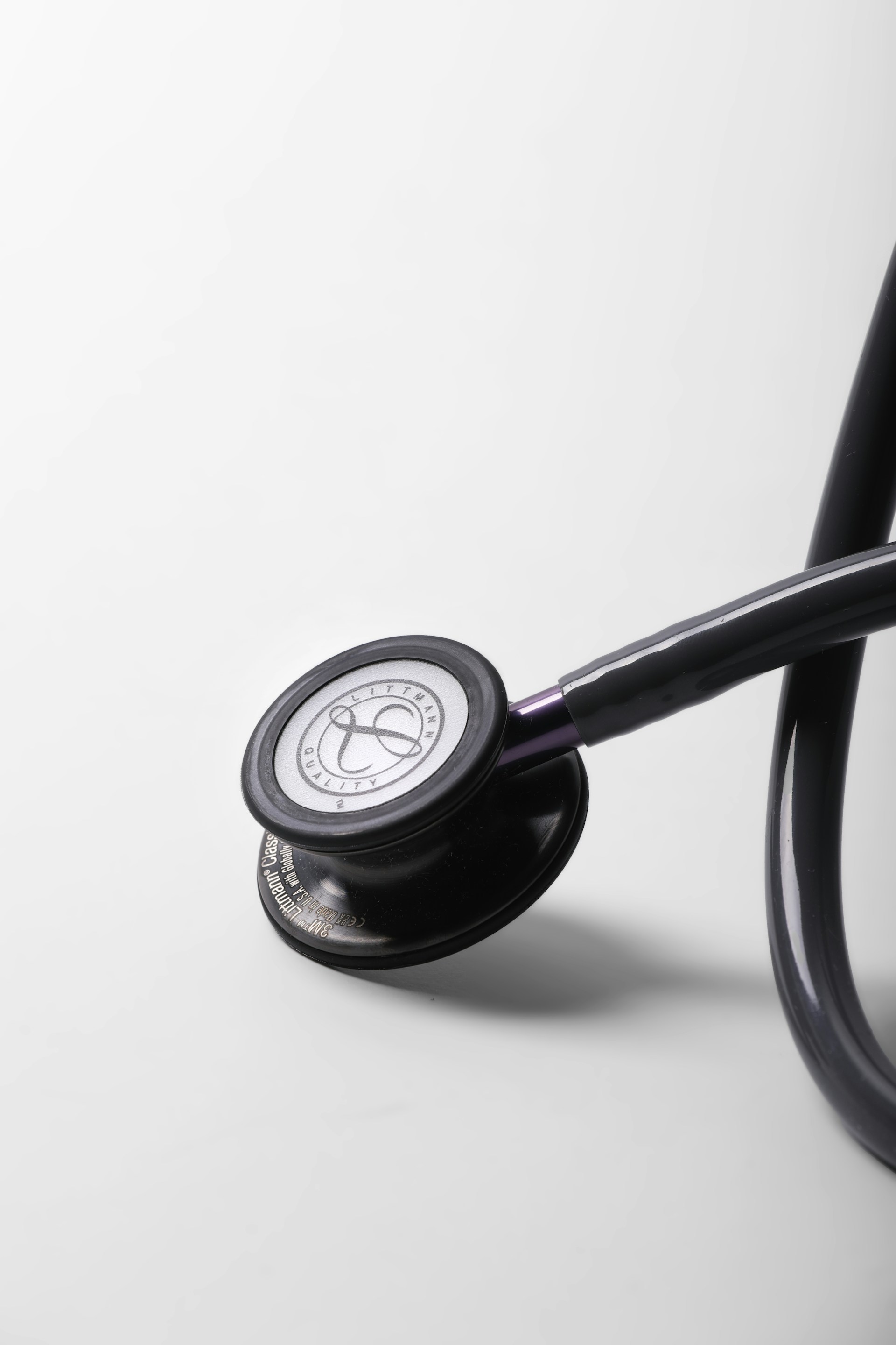 A black stethoscope rests on a white surface