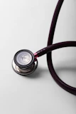 A close-up of a burgundy stethoscope on a white surface.