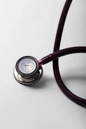 A close-up of a burgundy stethoscope on a white surface.
