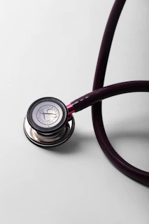 A close-up of a burgundy stethoscope on a white surface.