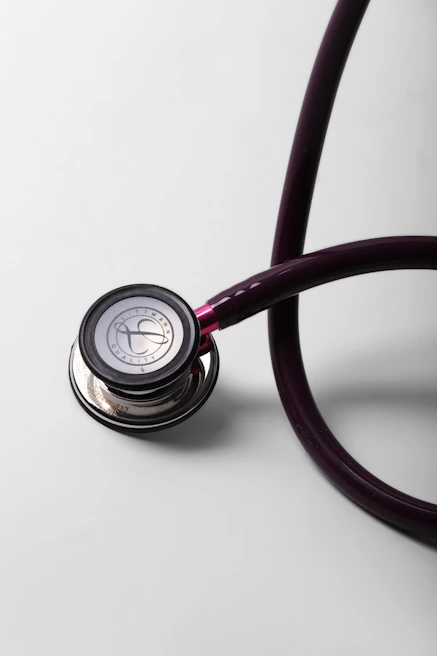 A close-up of a burgundy stethoscope on a white surface.