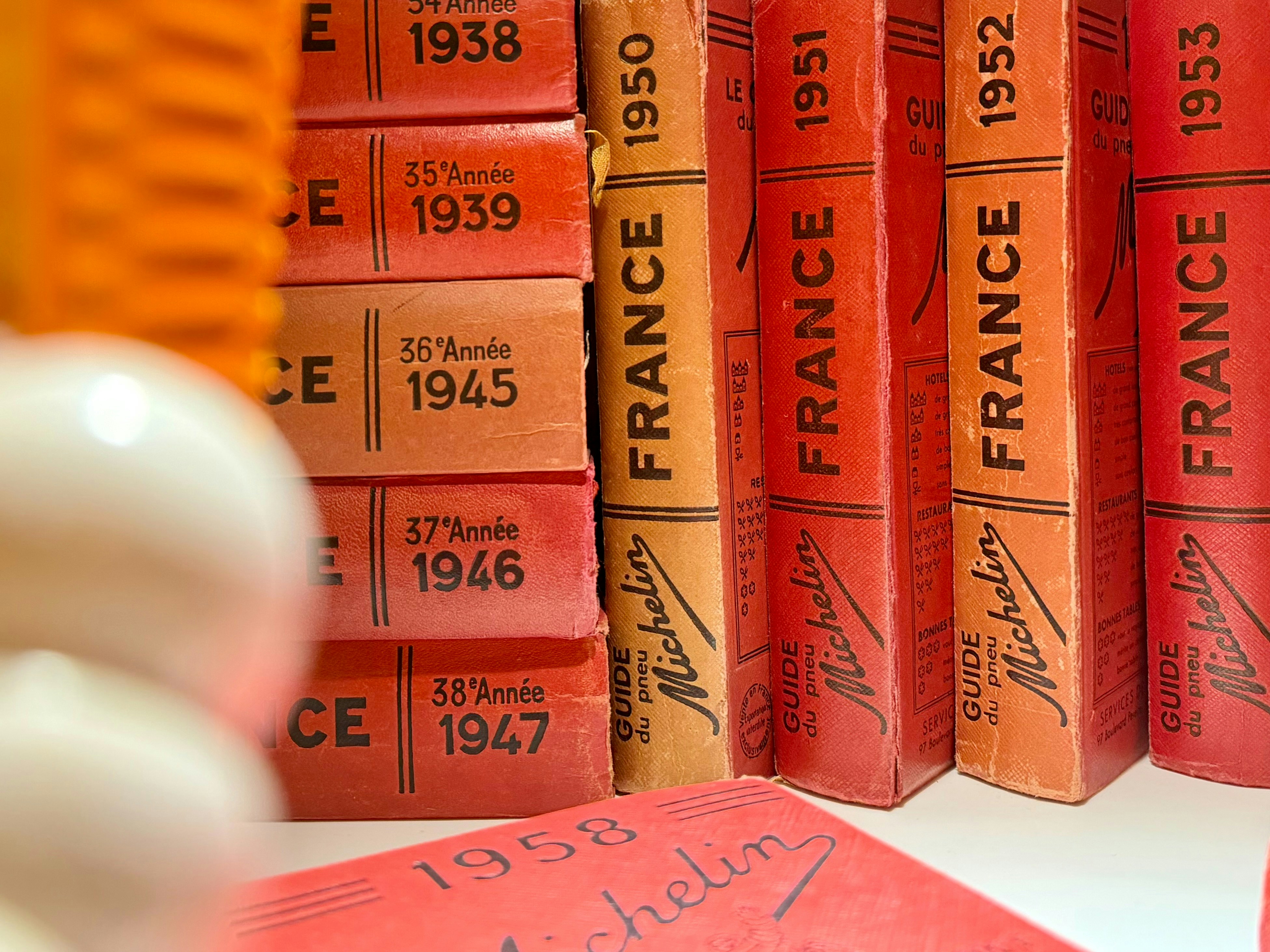 Vintage michelin guides stacked on a shelf.