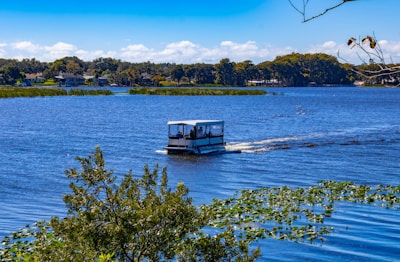 A small boat travels across a wide blue lake.