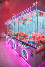 Row of colorful claw machines filled with plush toys.