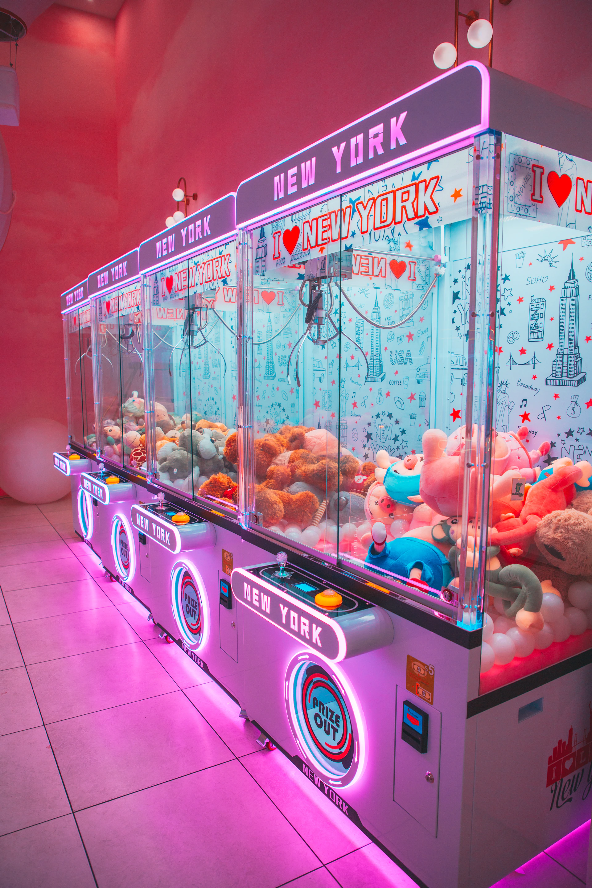 Row of colorful claw machines filled with plush toys.
