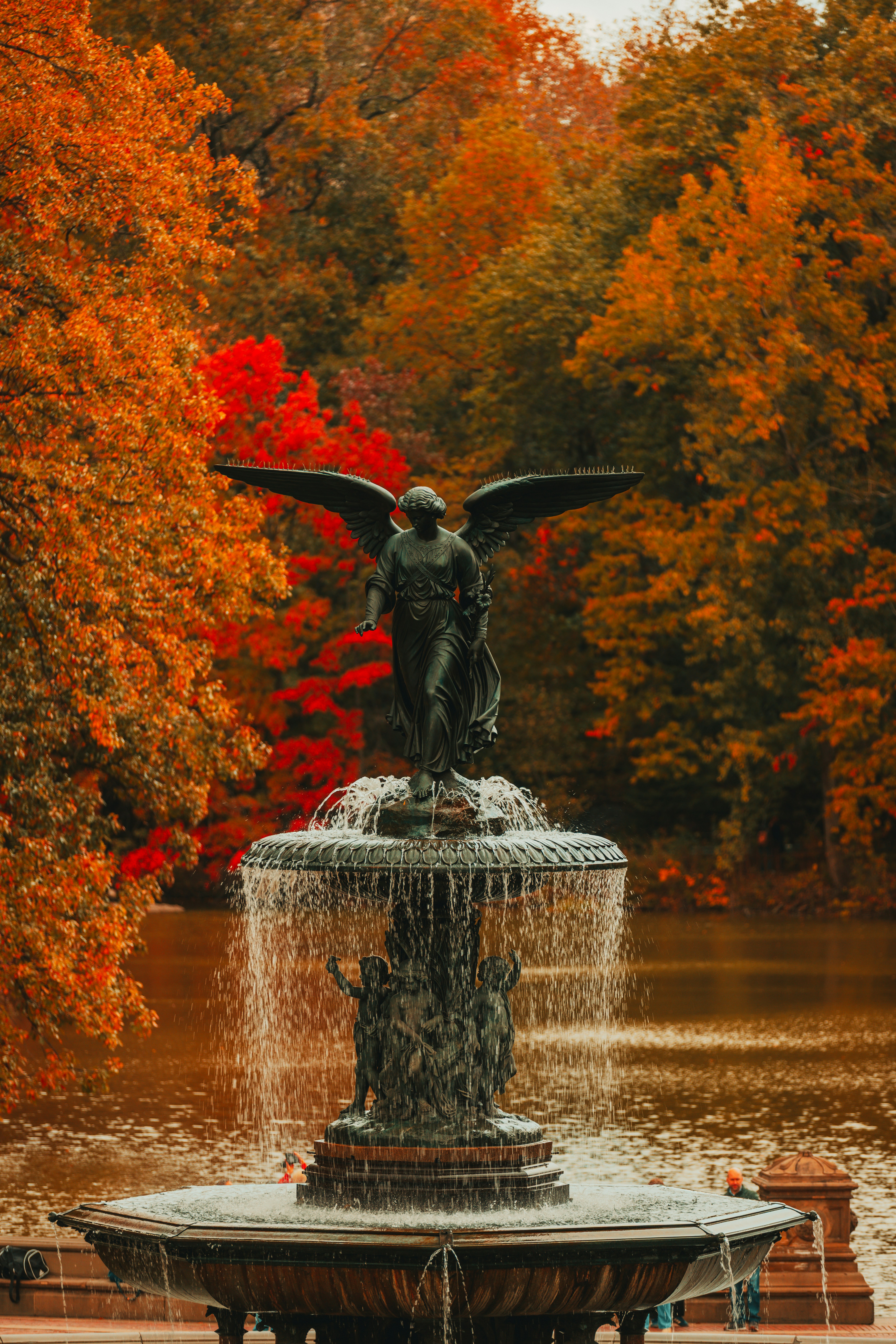 Engelsbrunnen, umgeben von Herbstbäumen und Wasser.