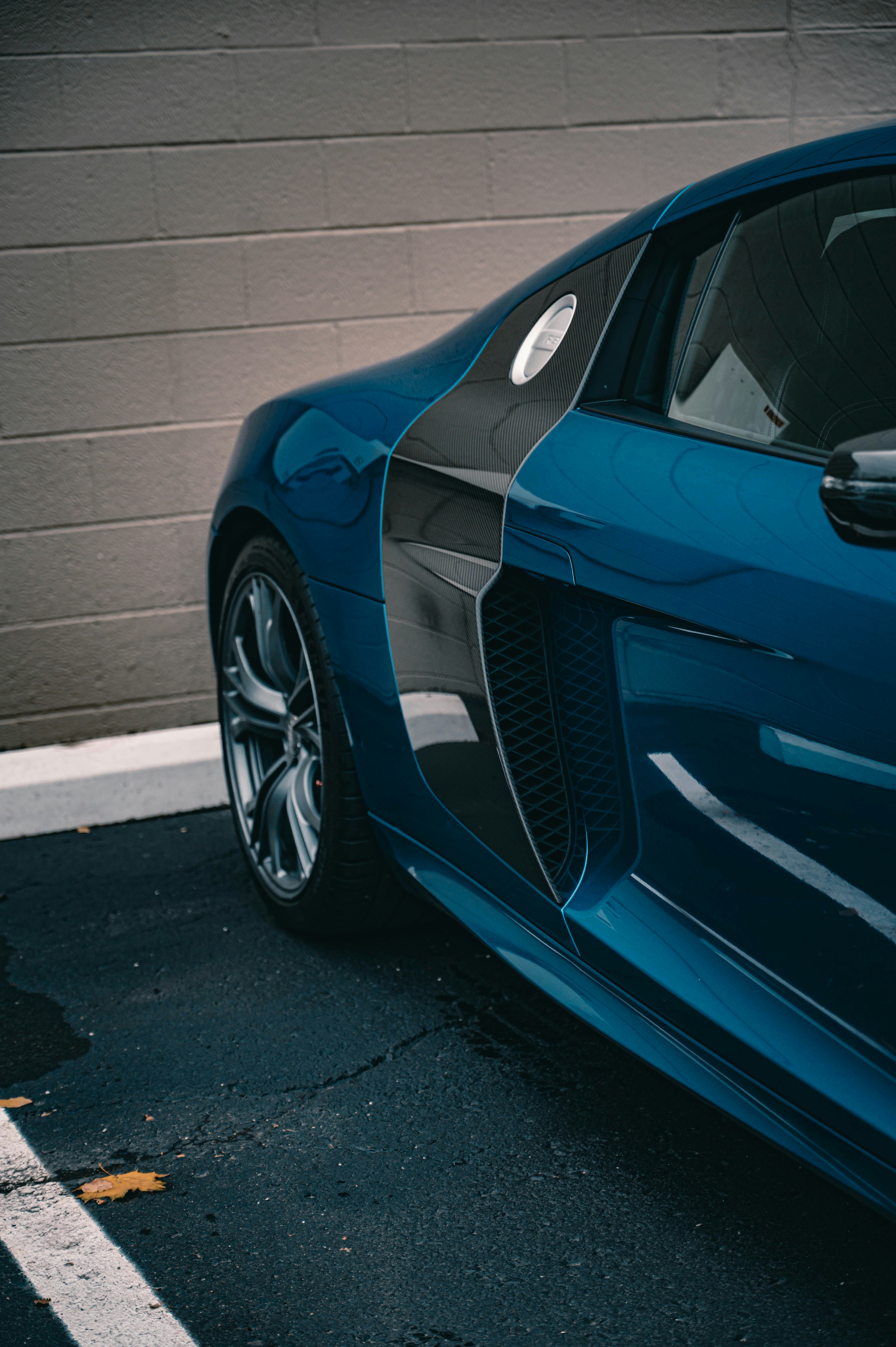 A sleek blue sports car parked against a brick wall.