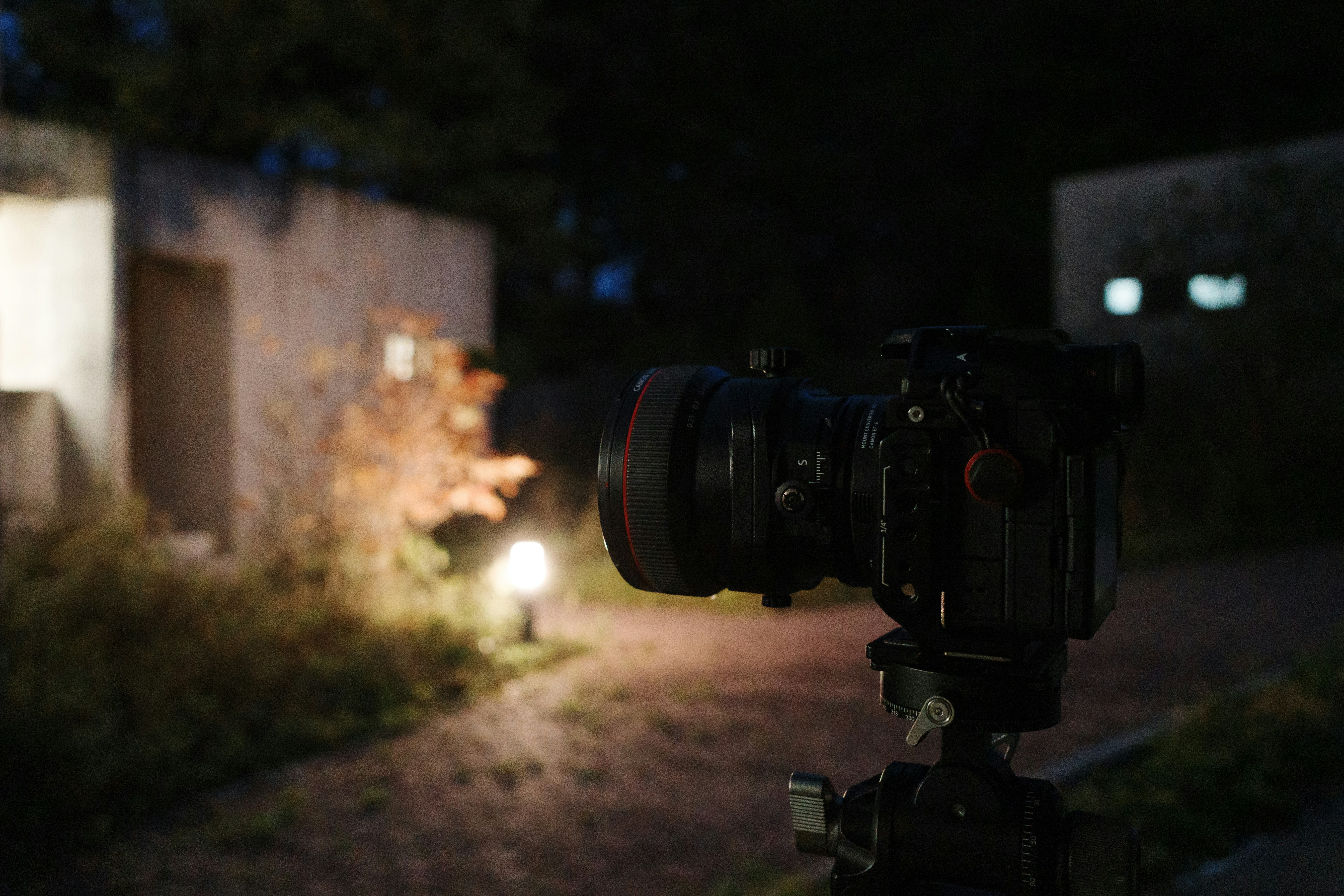 Camera on tripod at night with illuminated building