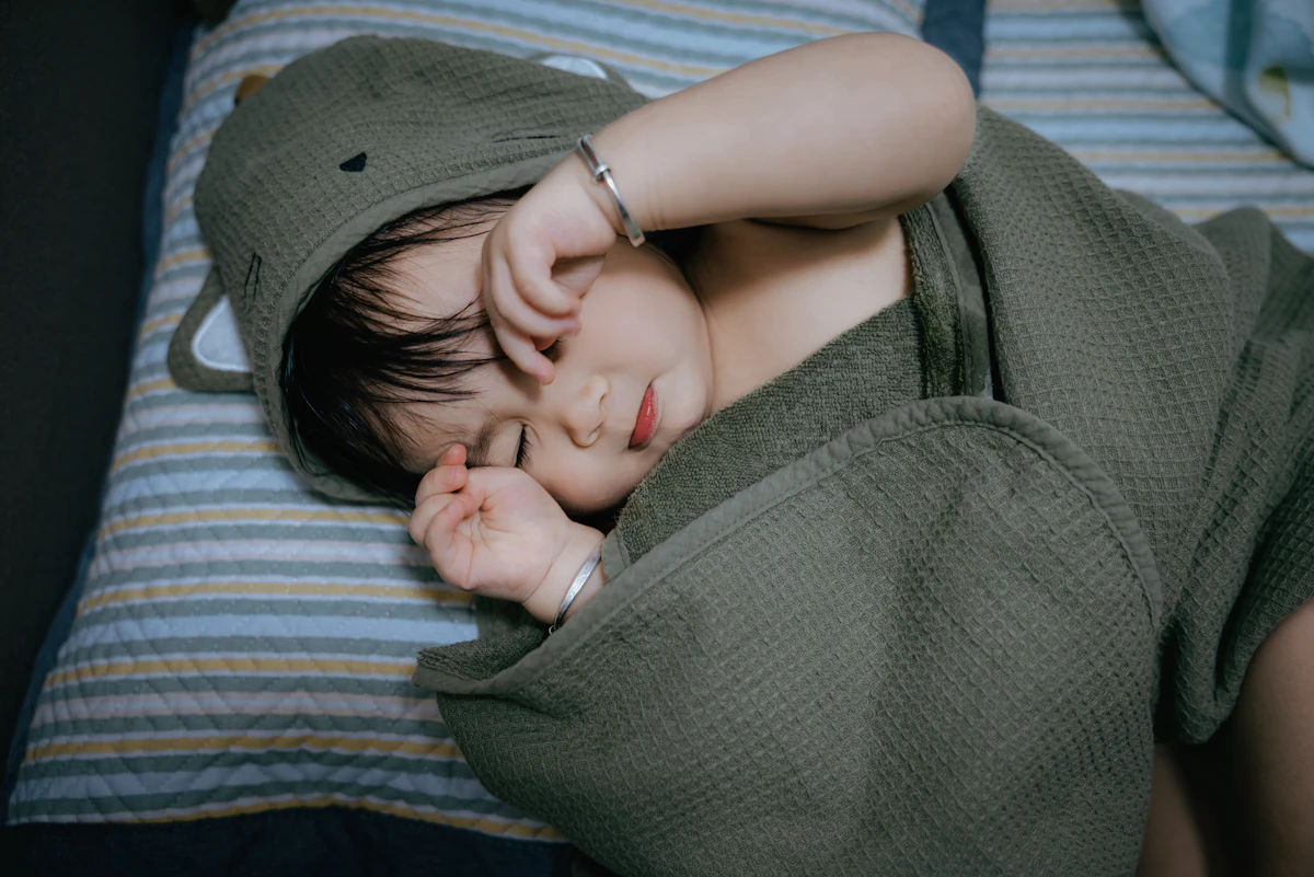 Baby sleeping peacefully wrapped in a hooded towel.
