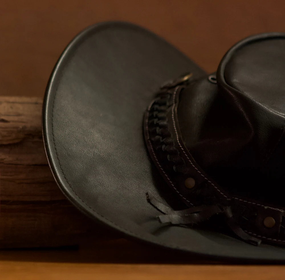 A black felt cowboy hat resting crown down on bare wood.