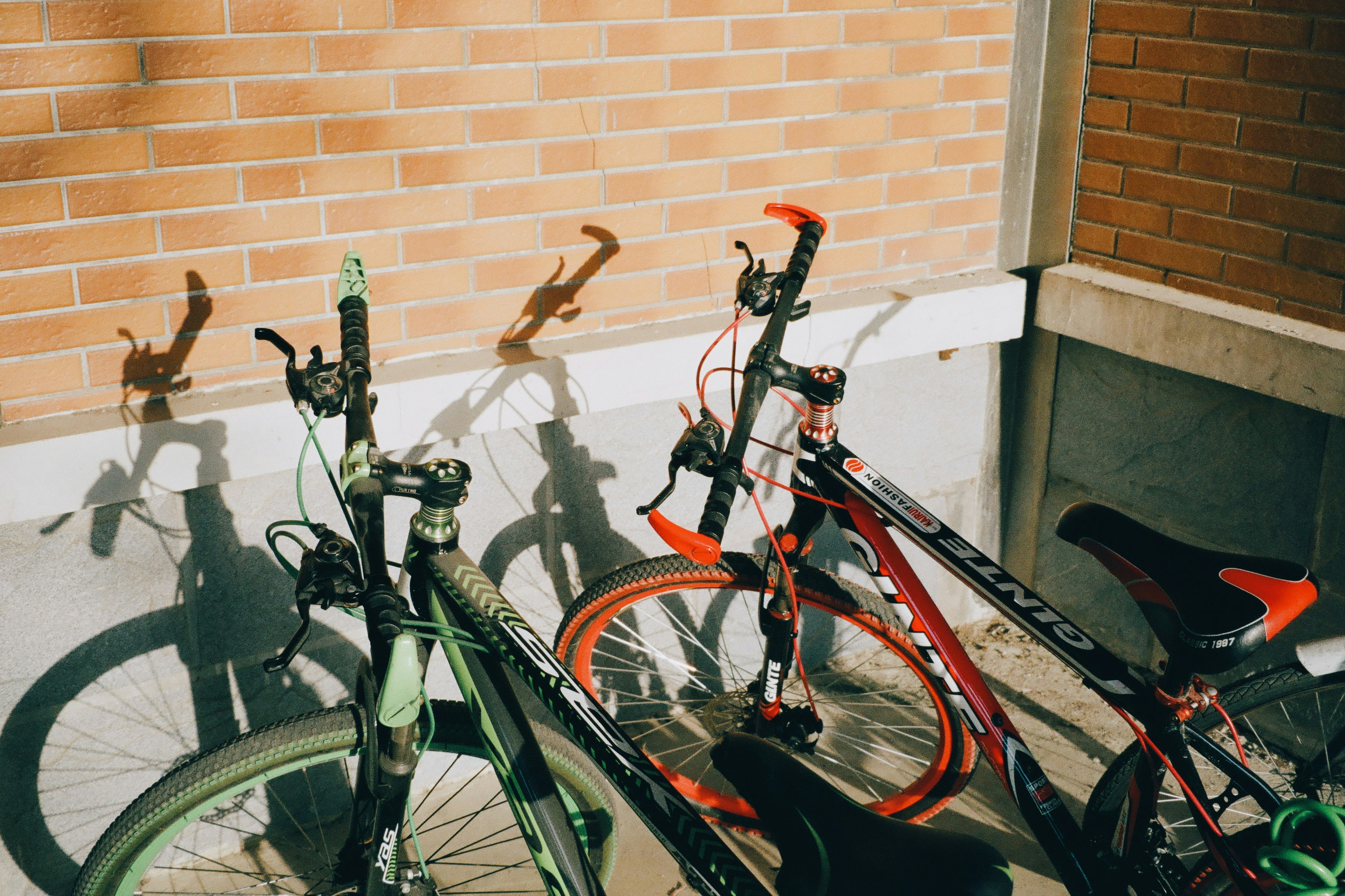 Two bicycles parked against a brick wall.