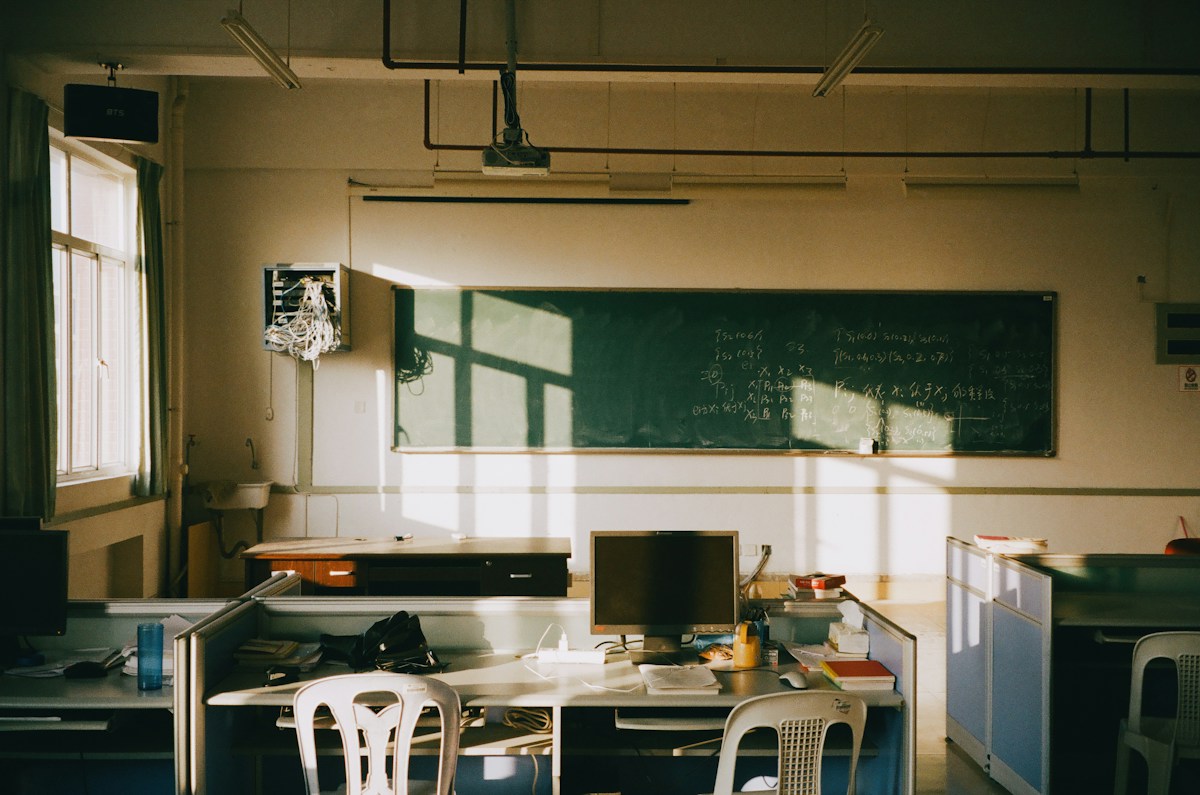 Sunlit empty classroom with rows of desks, ideal for parent-teacher conference scheduling discussions.