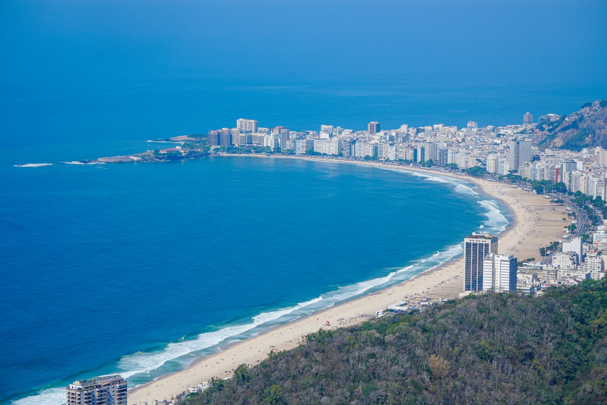 Curved Beach With Cityscape And Blue Ocean.