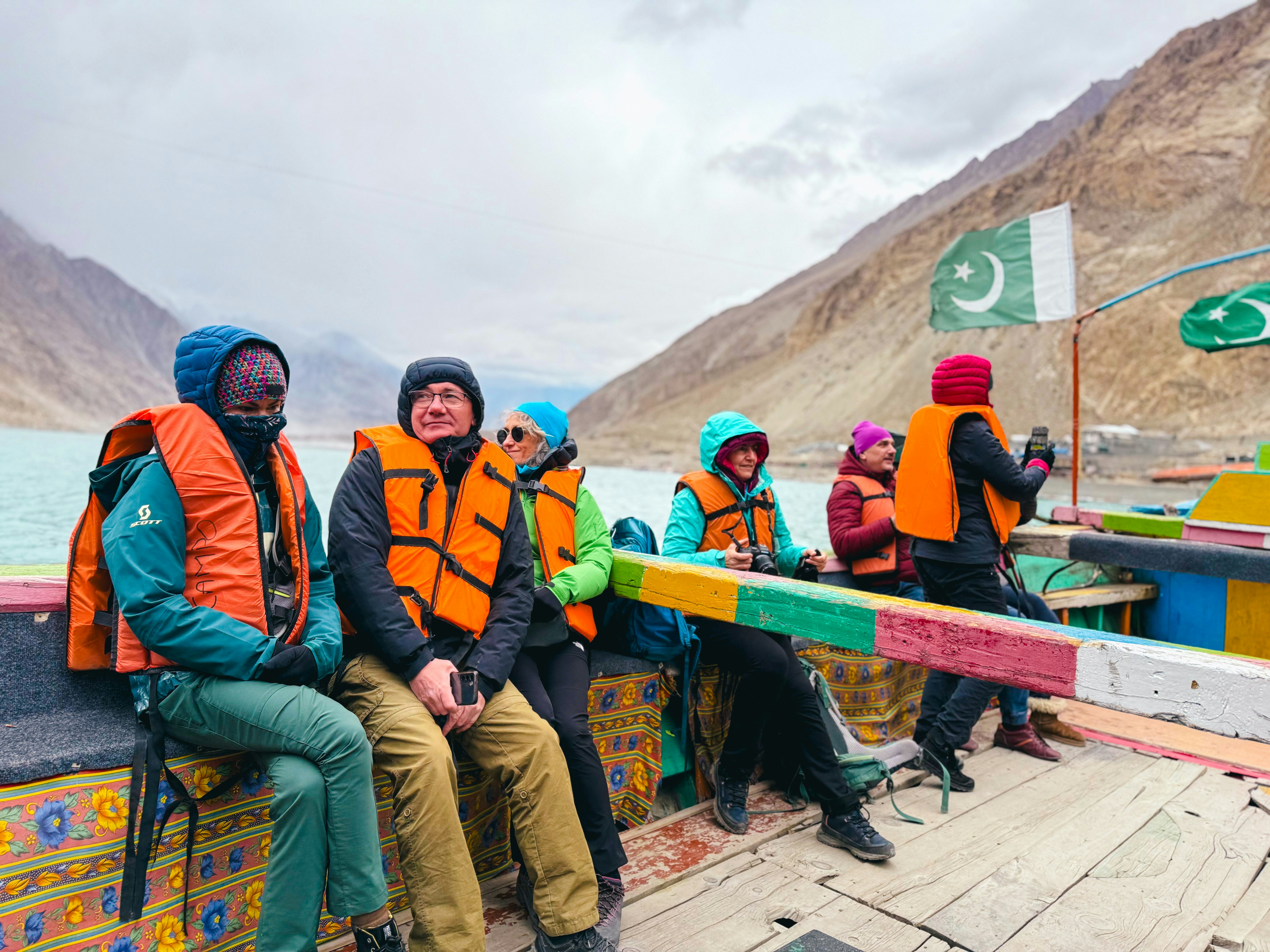 People in life jackets on a boat with mountains.