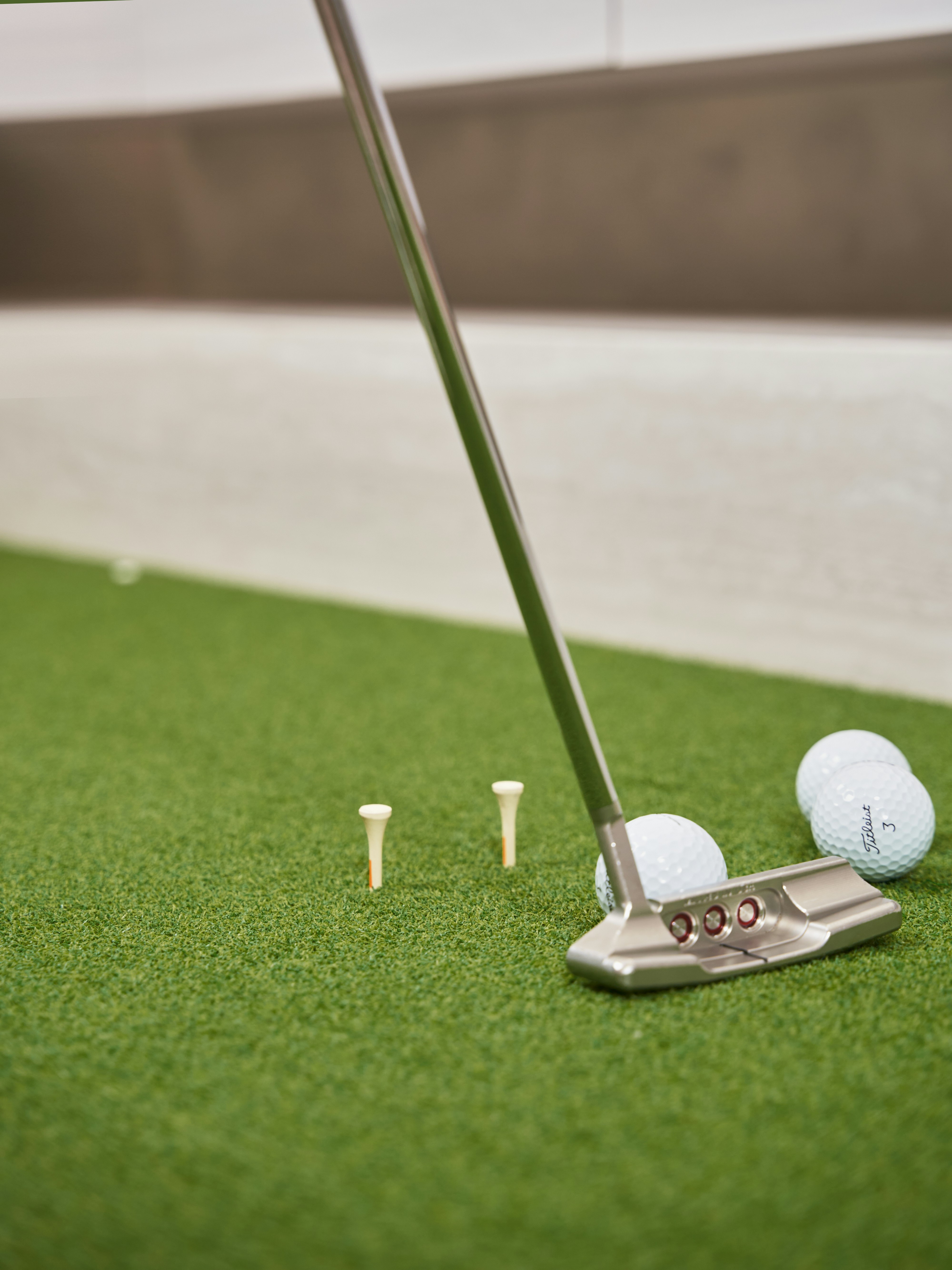 Golf putter with balls and tees on green turf
