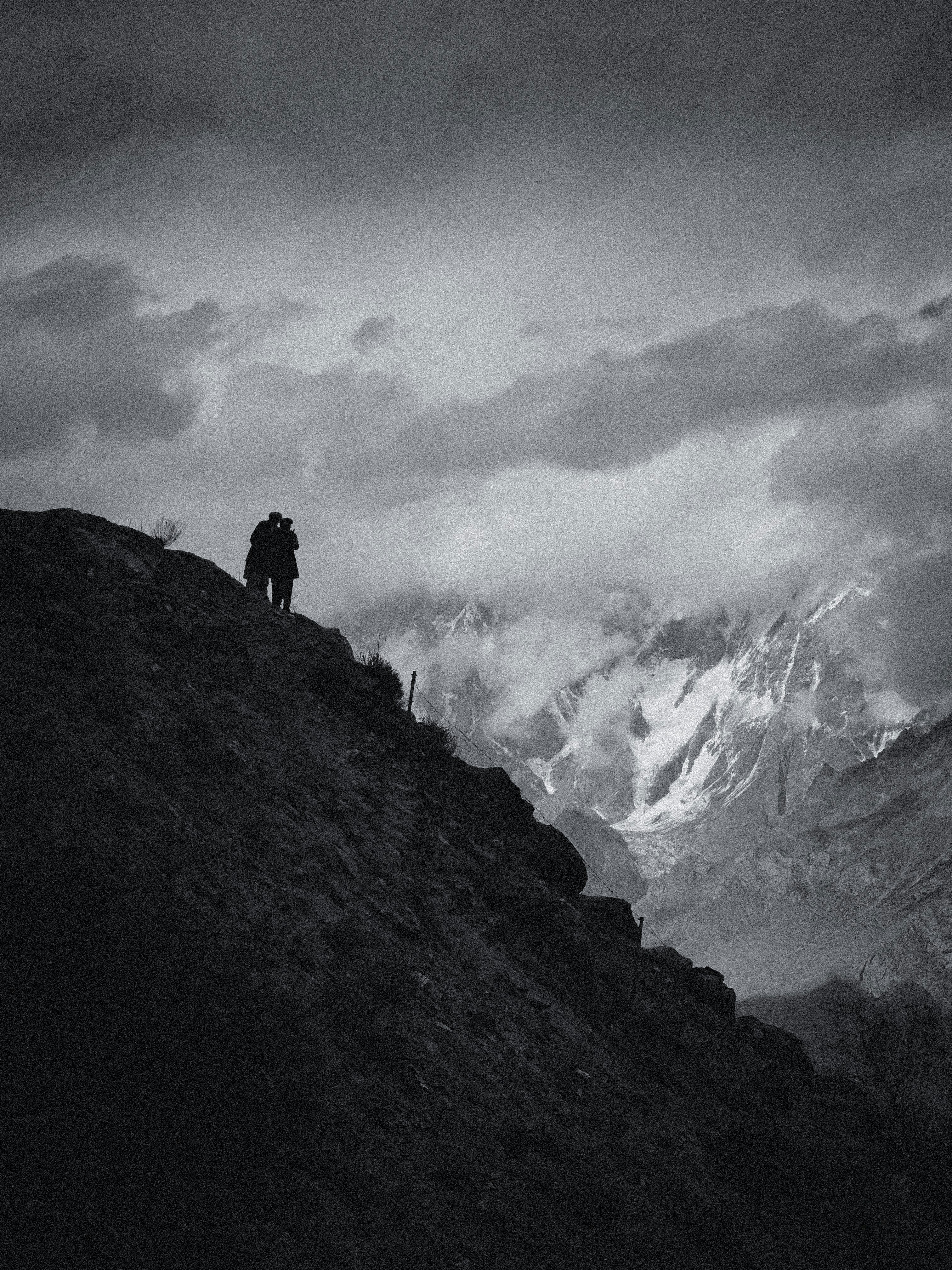 Two figures stand on a mountain slope