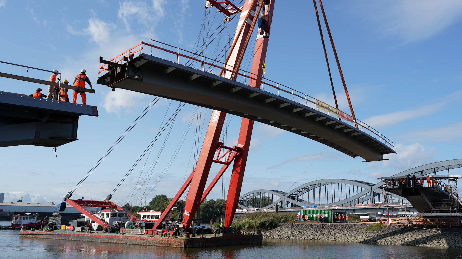 Crane lifting bridge section over water