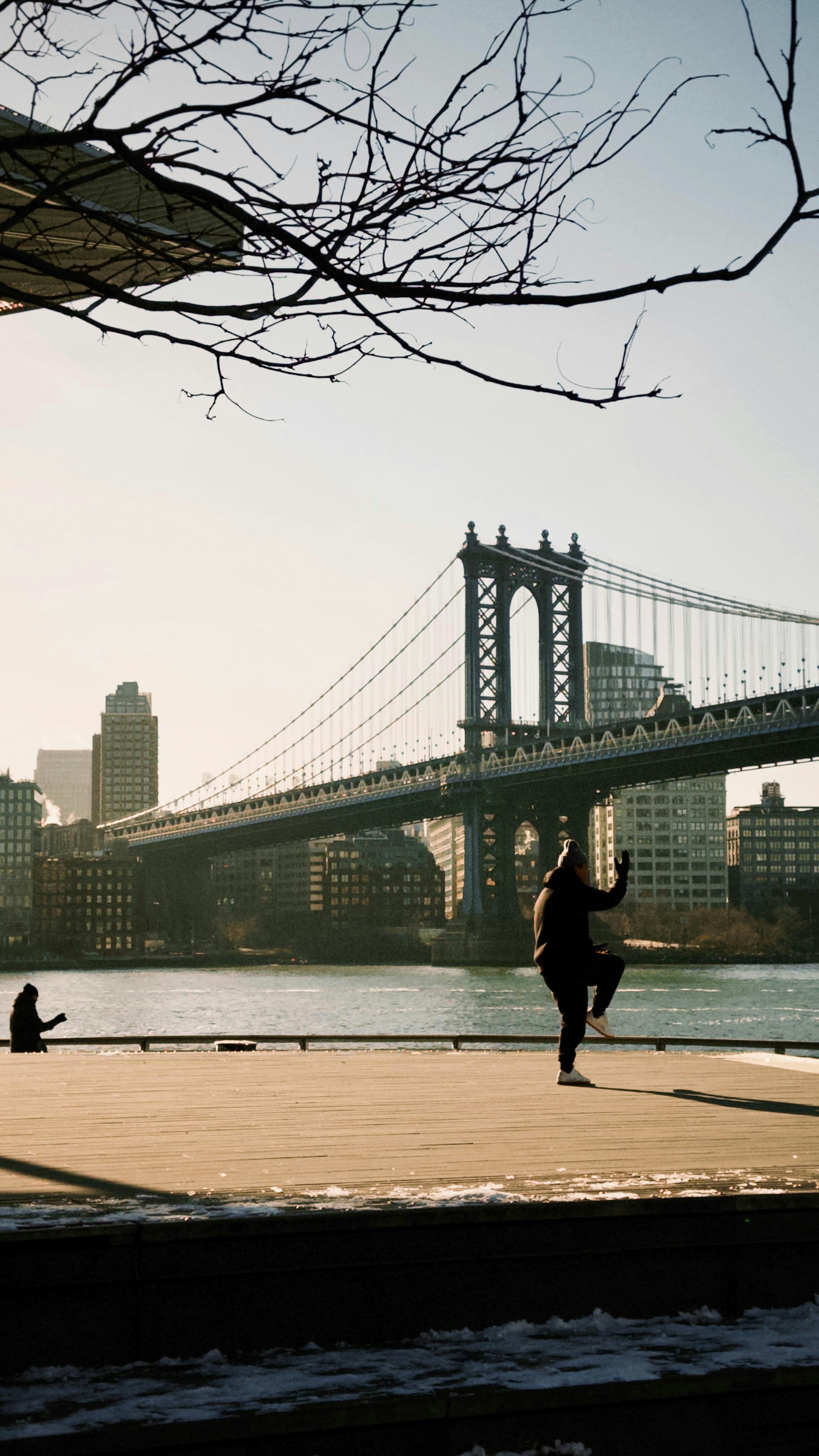 Two people exercise by a bridge at sunrise.