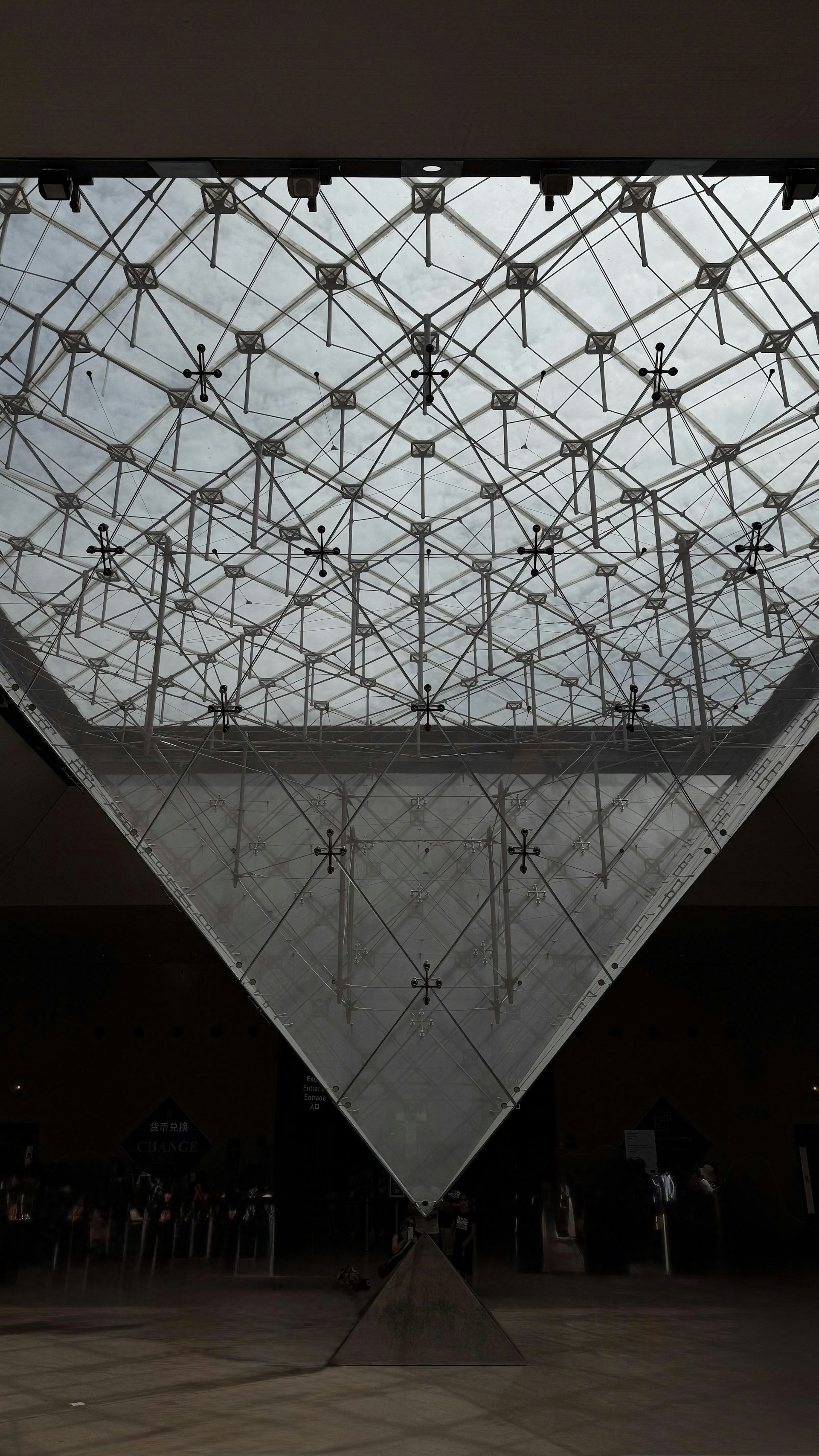 Glass pyramid structure against a cloudy sky