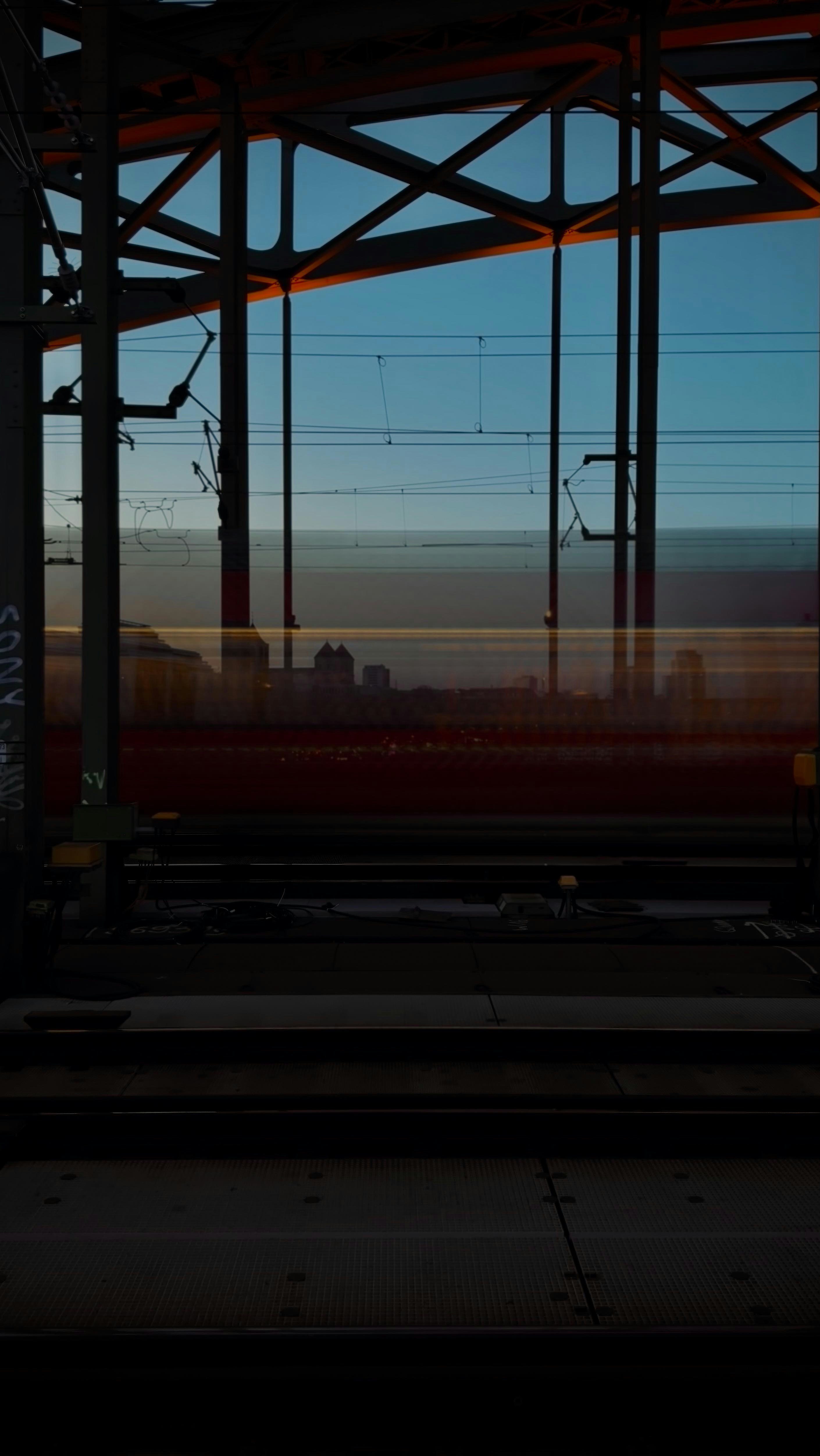 Train moving under industrial bridge at sunset