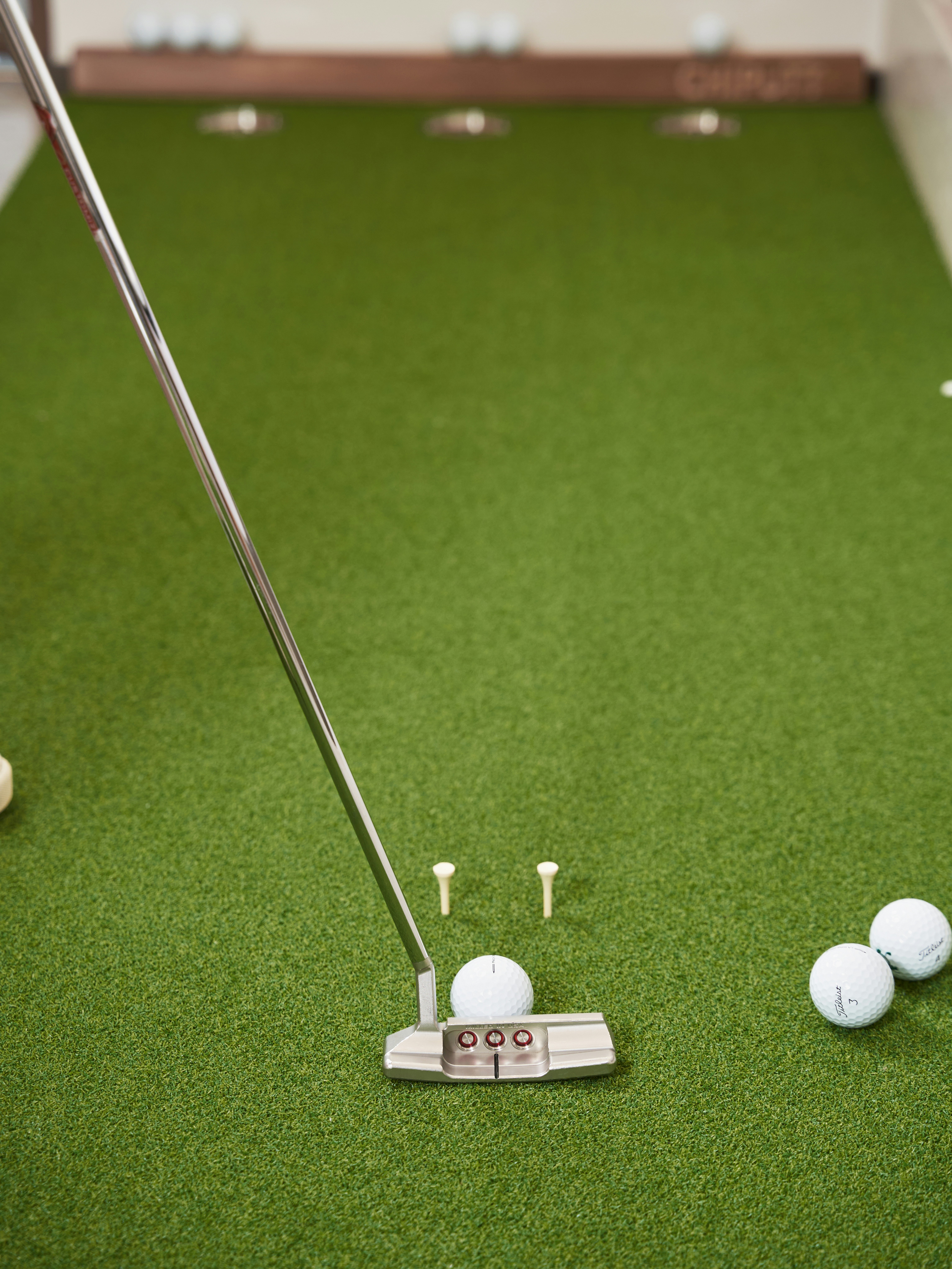 Golf putter and balls on green turf