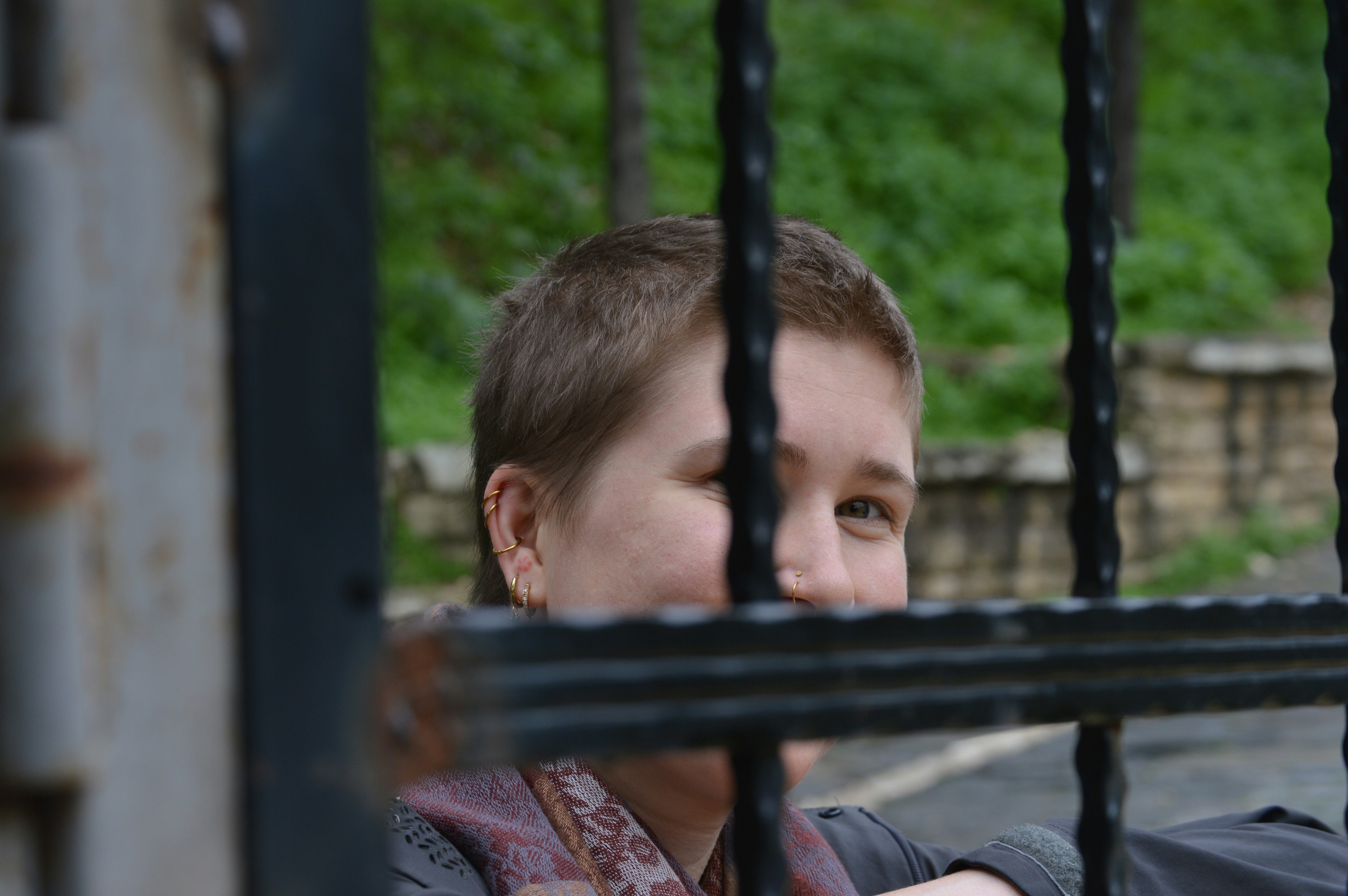 Person peeking through metal bars outdoors