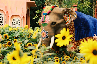 Decorated elephant stands in a field of sunflowers.