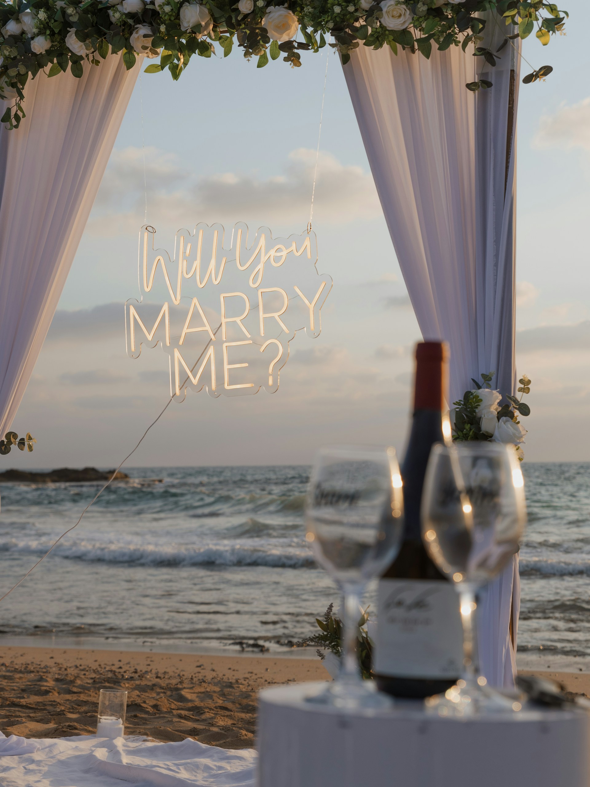 Marriage proposal setup on a beach at sunset.