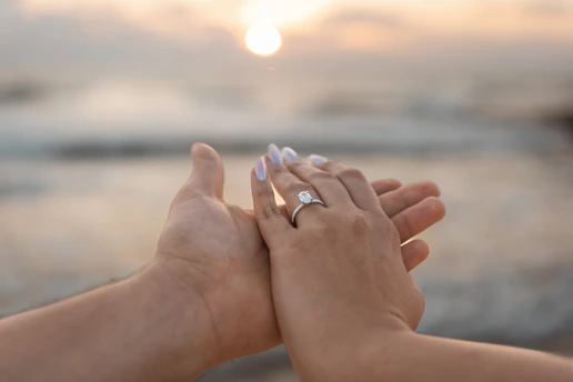 Couple's hands with engagement ring at sunset