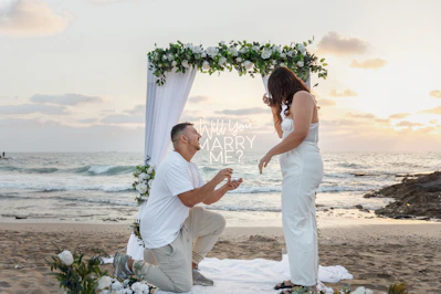 Man proposes to woman on beach at sunset.