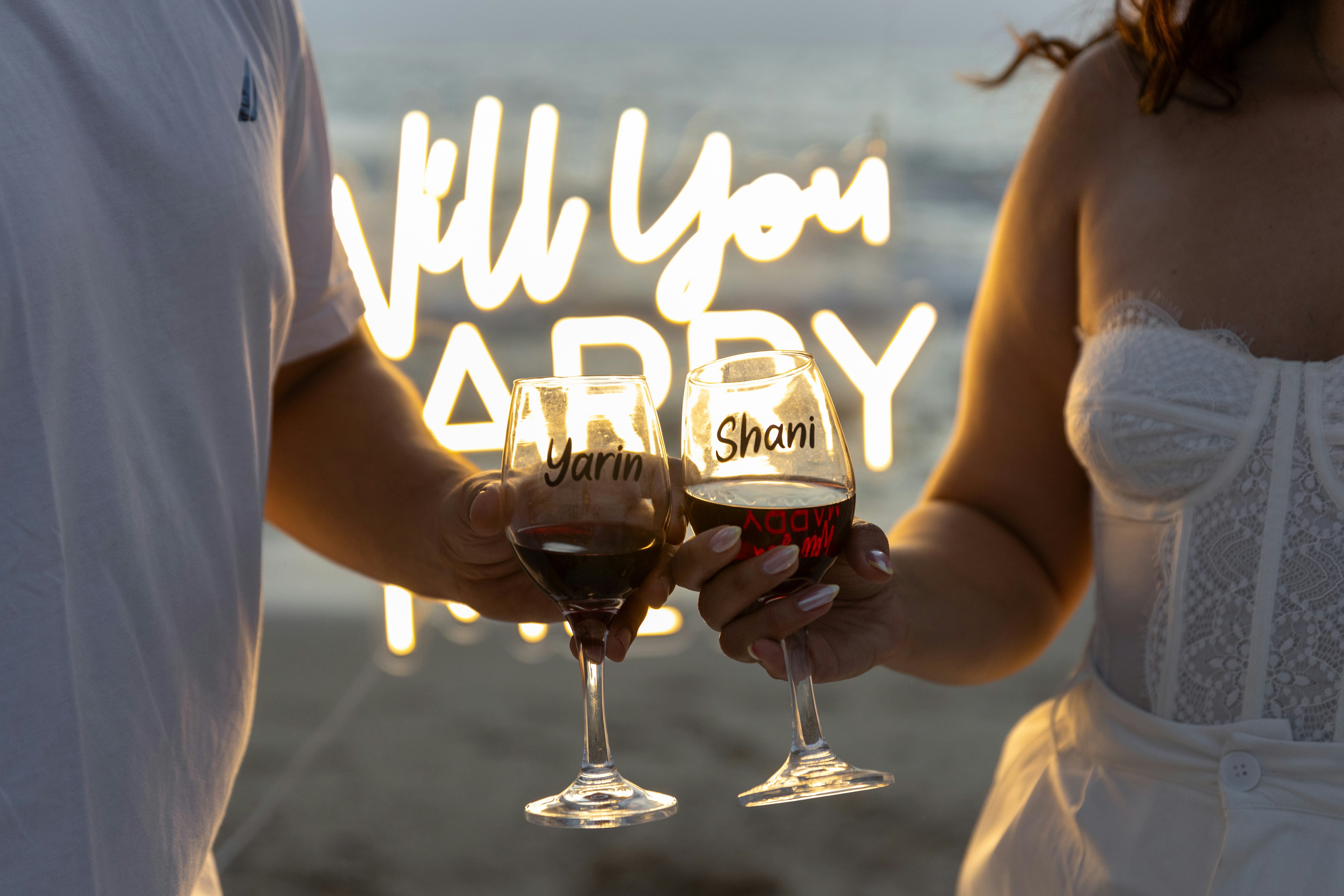 Couple toasting with wine glasses at sunset proposal