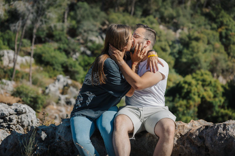 Couple kissing outdoors with lush green foliage