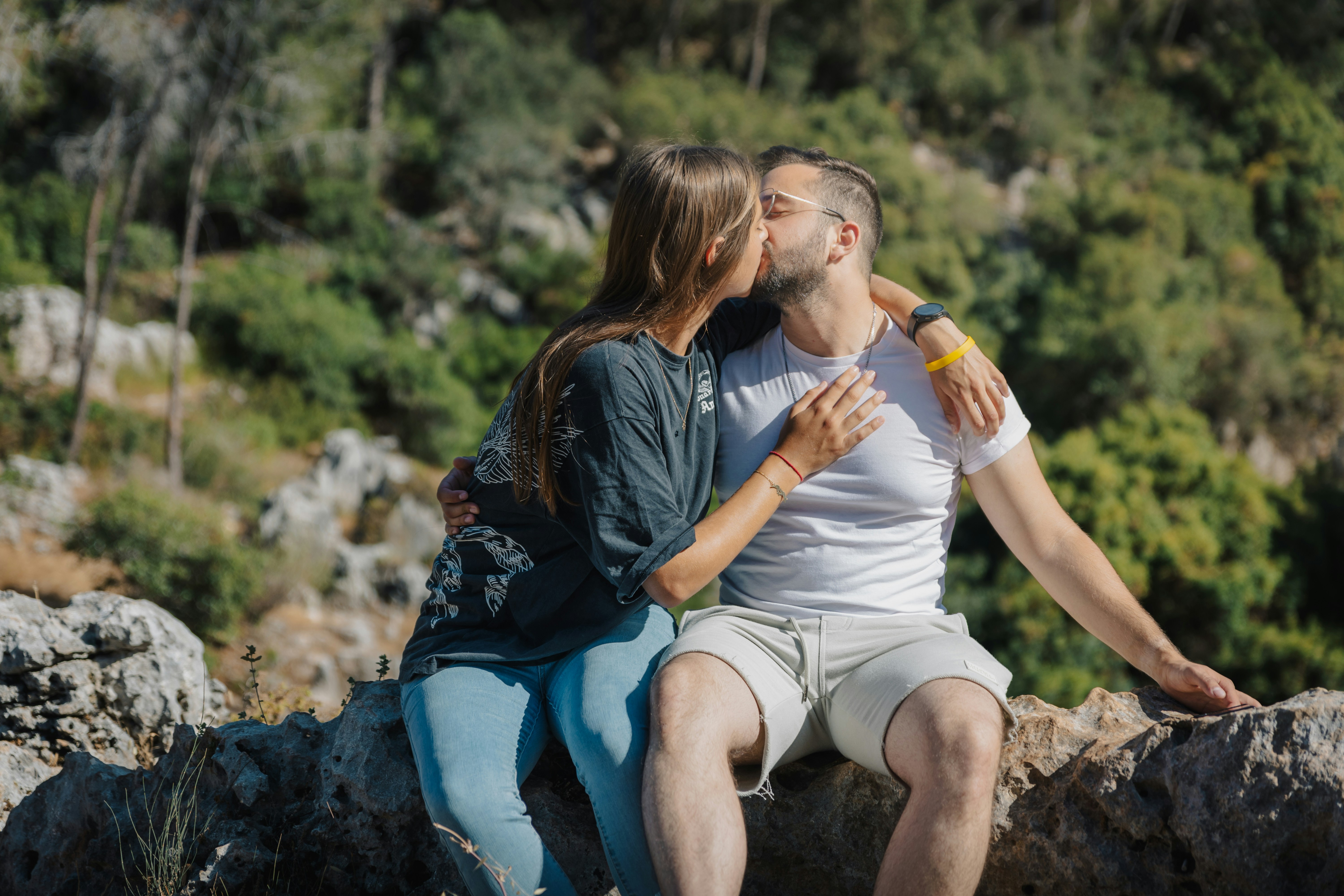 Couple kissing outdoors with rocky hillside background