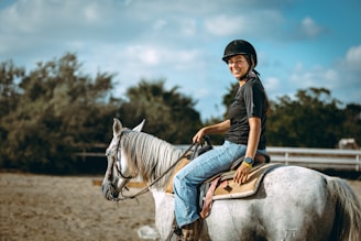 Woman smiling while riding a white horse