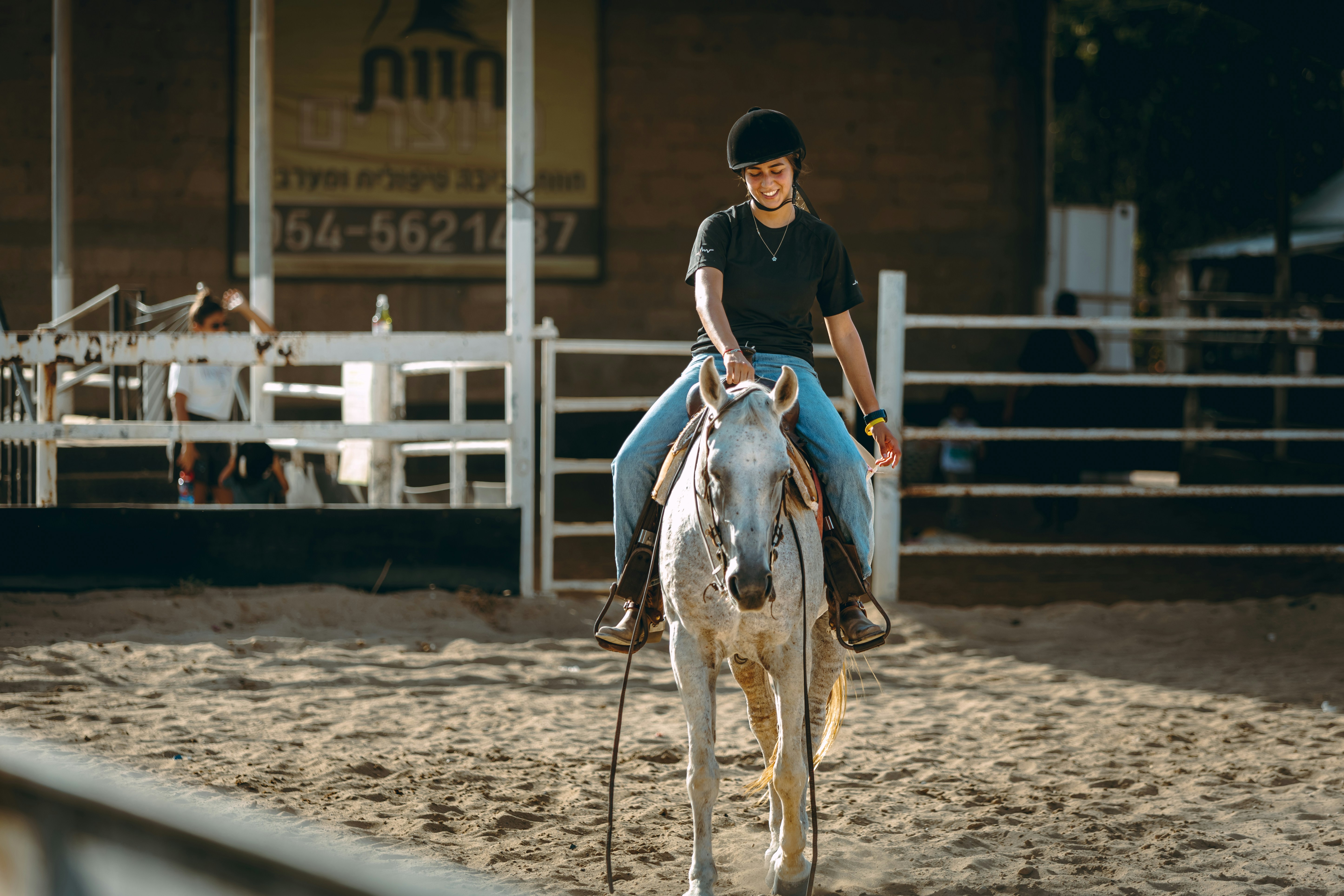 Woman riding a white horse in an arena.