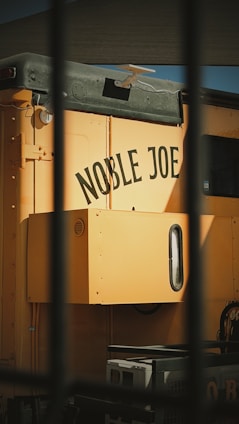 Yellow train car with "noble joe" painted on side.