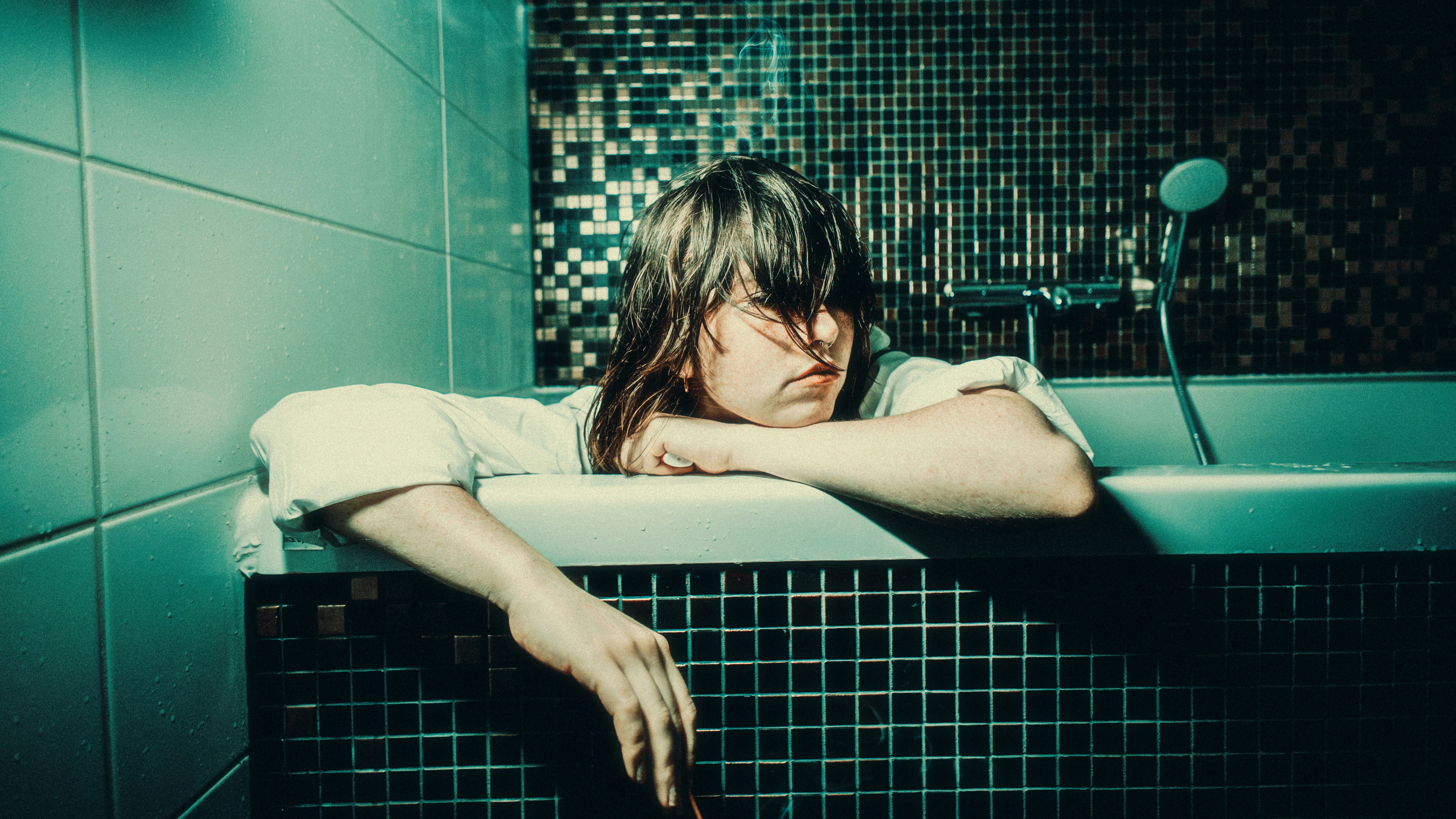 Woman with wet hair leaning over bathtub