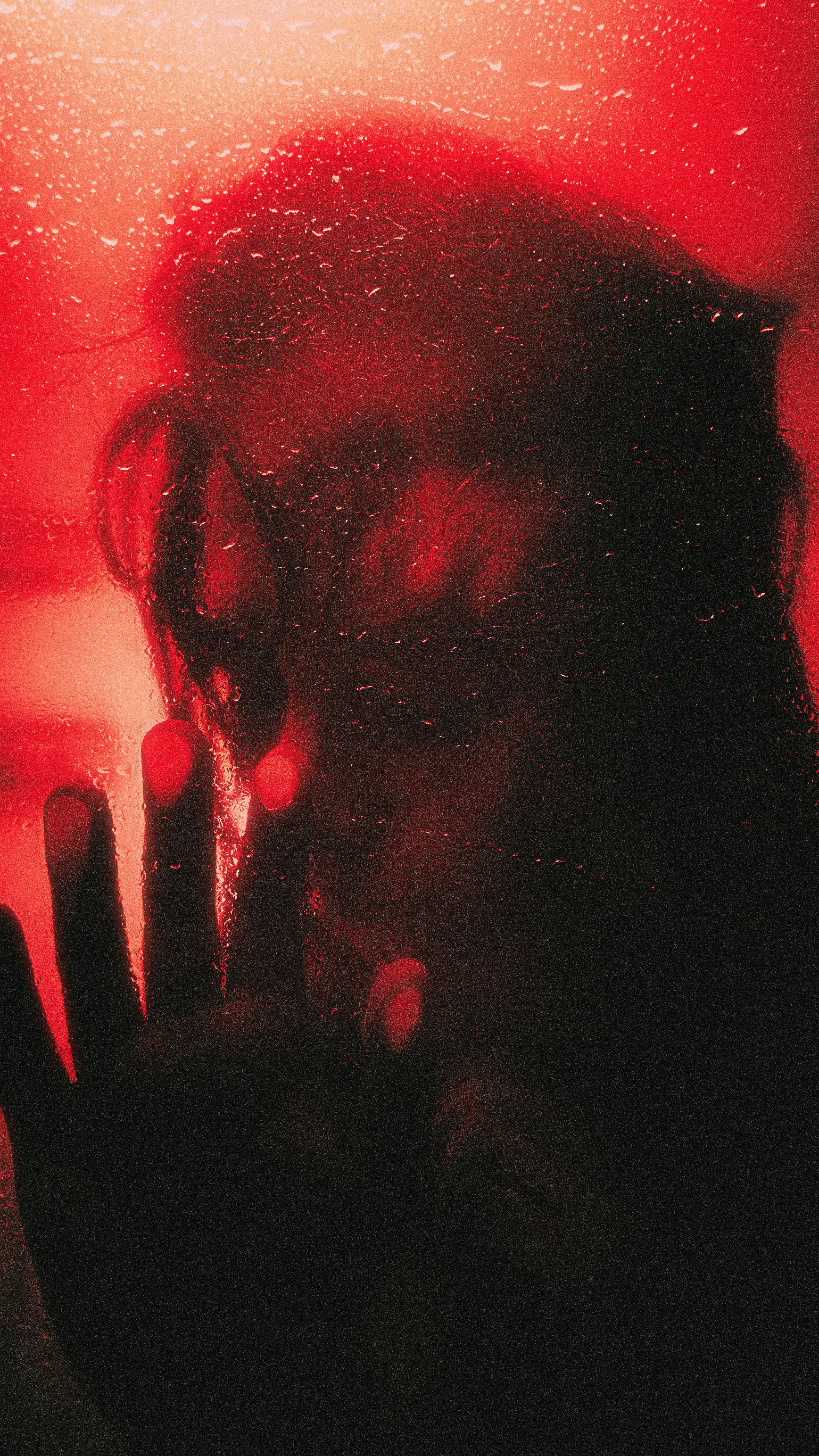 Silhouette of a person's face behind a wet surface.