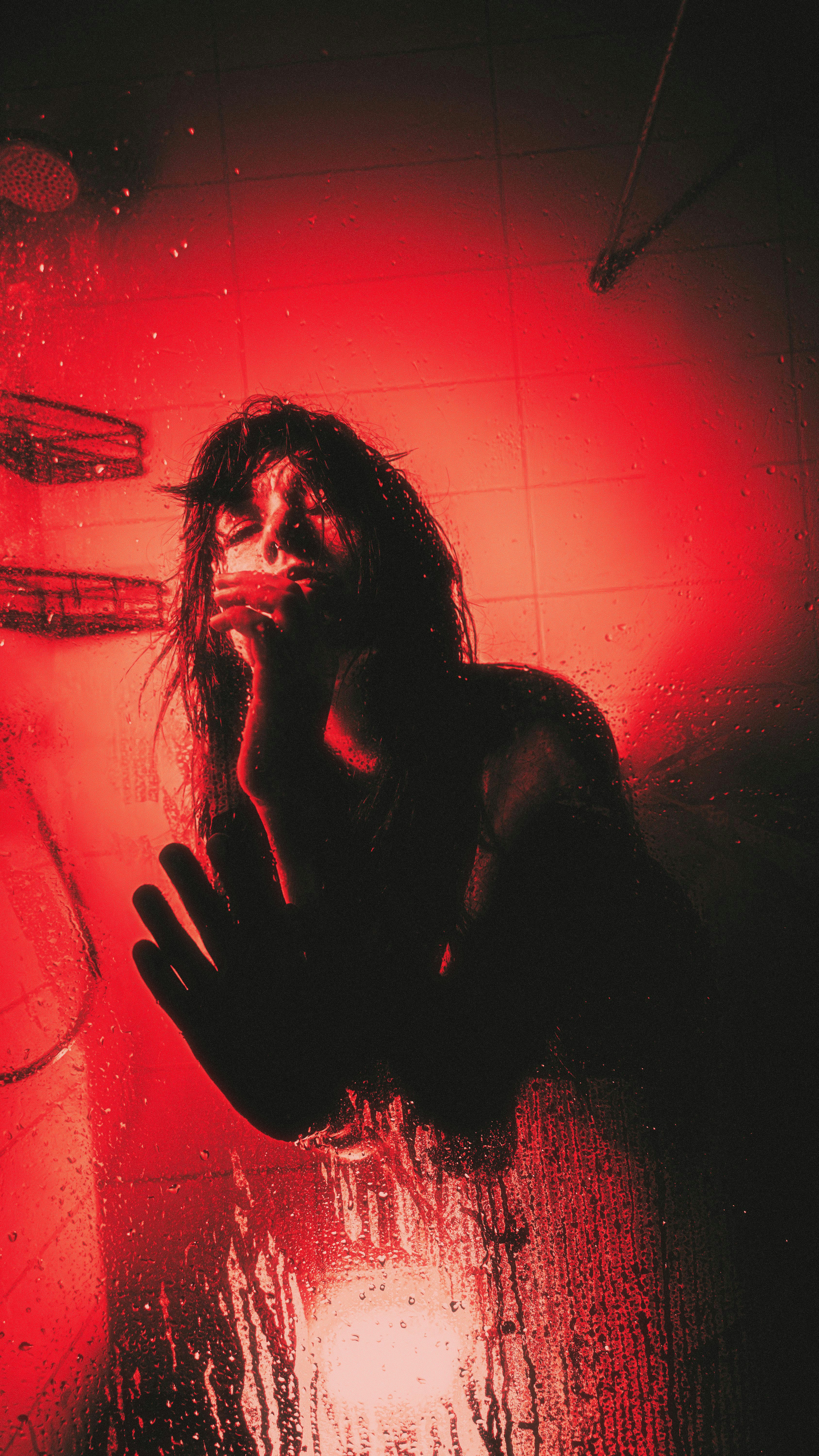 Woman in shower with red lighting and water drops