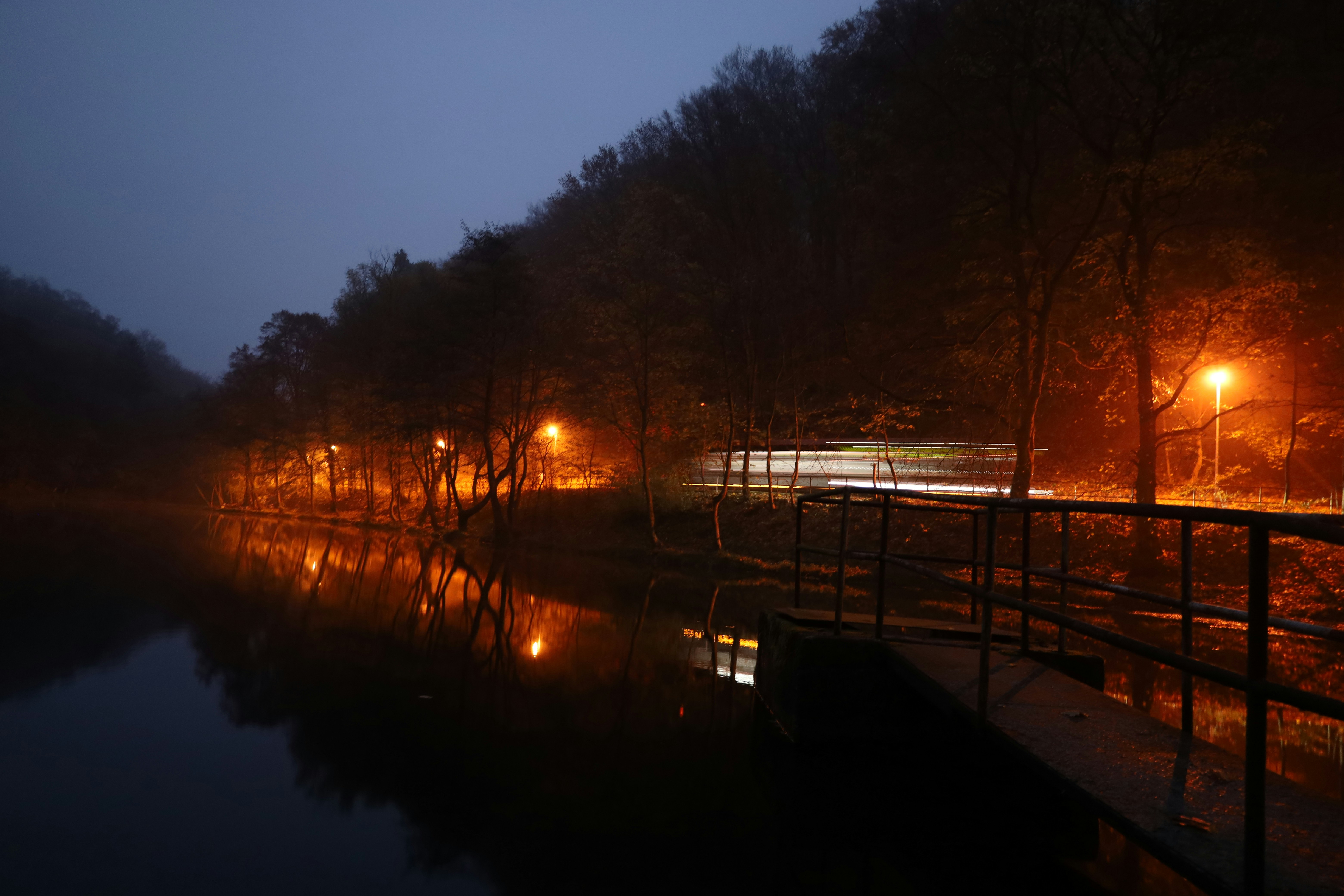 Streetlights reflect on a misty lake at night