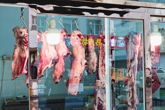 Raw meat hanging in a butcher shop window.