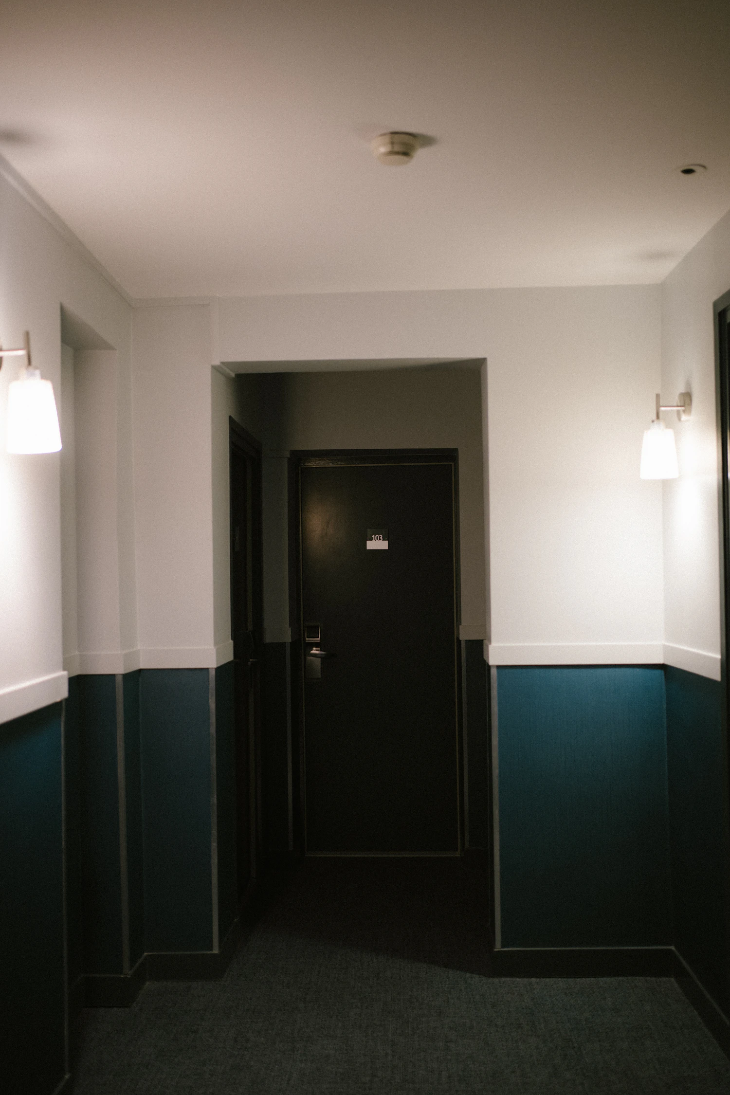 A corridor with a deep green painted dado and a dark panelled door