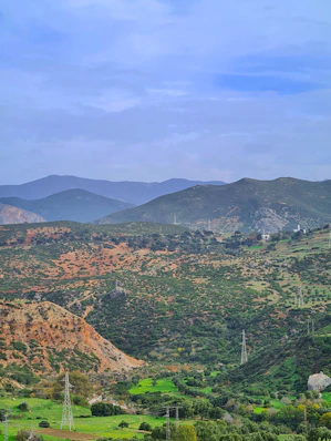 Rolling green hills and mountains under a cloudy sky.