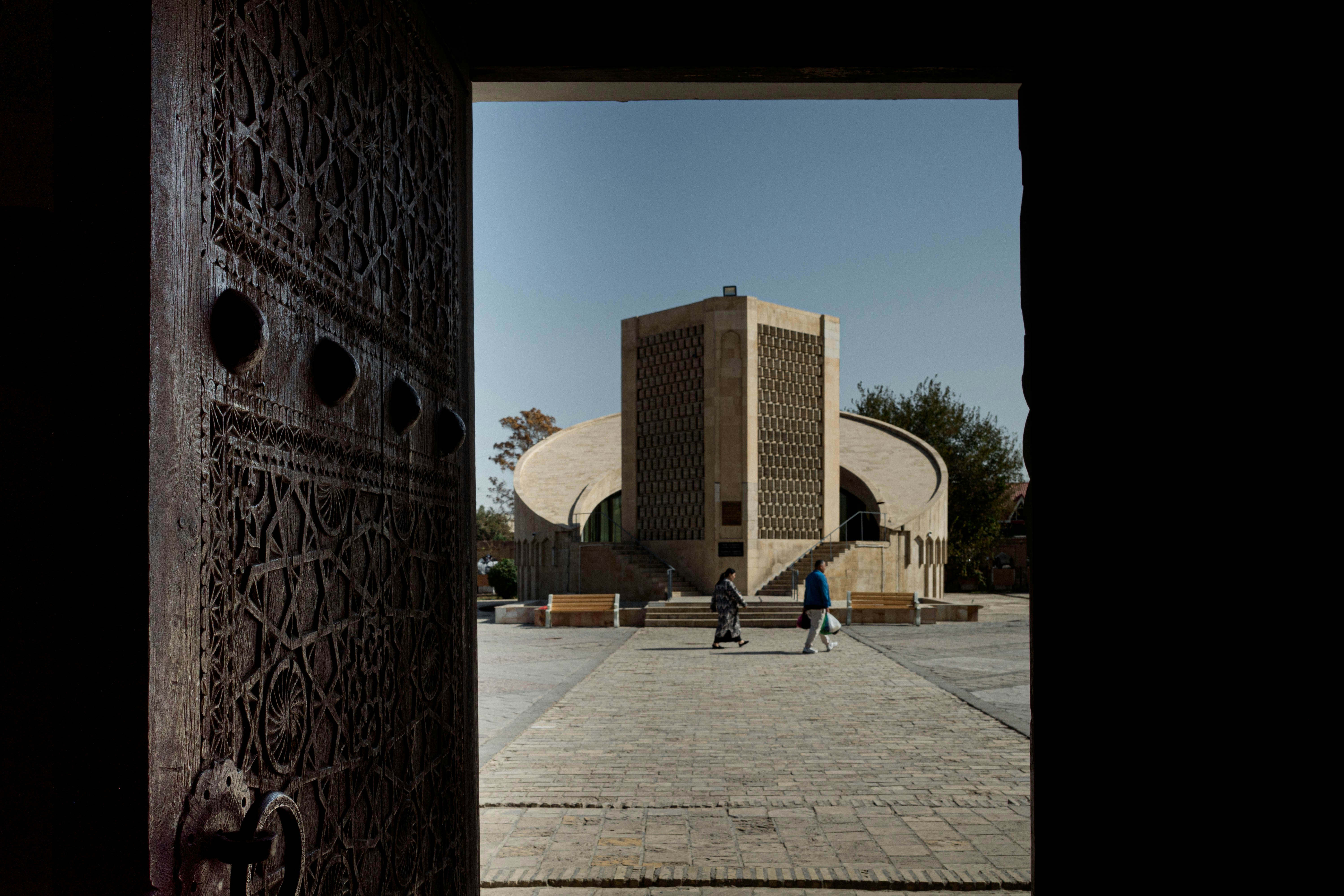 View through ornate wooden door to modern building