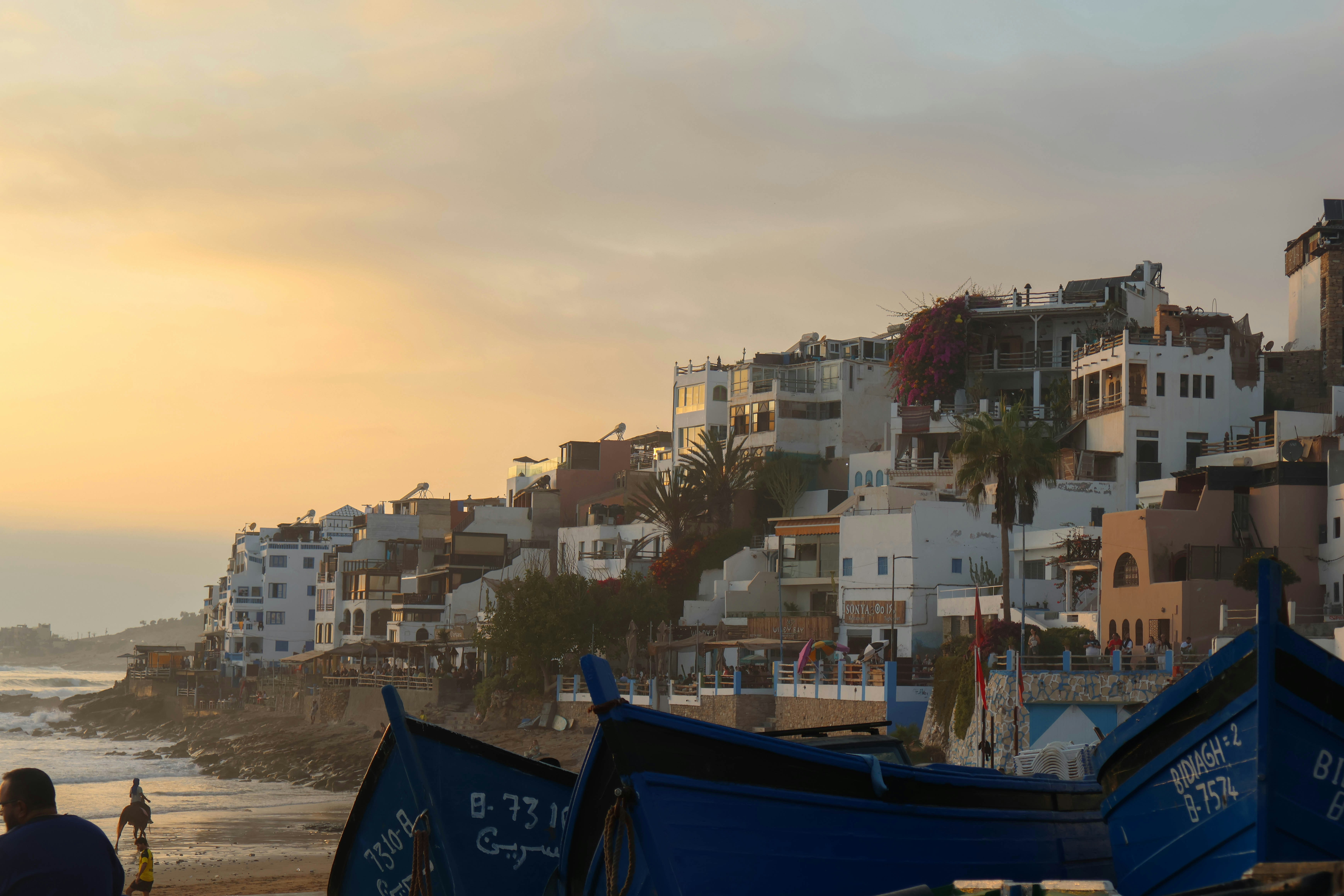Coastal town with white buildings and blue boats at sunset