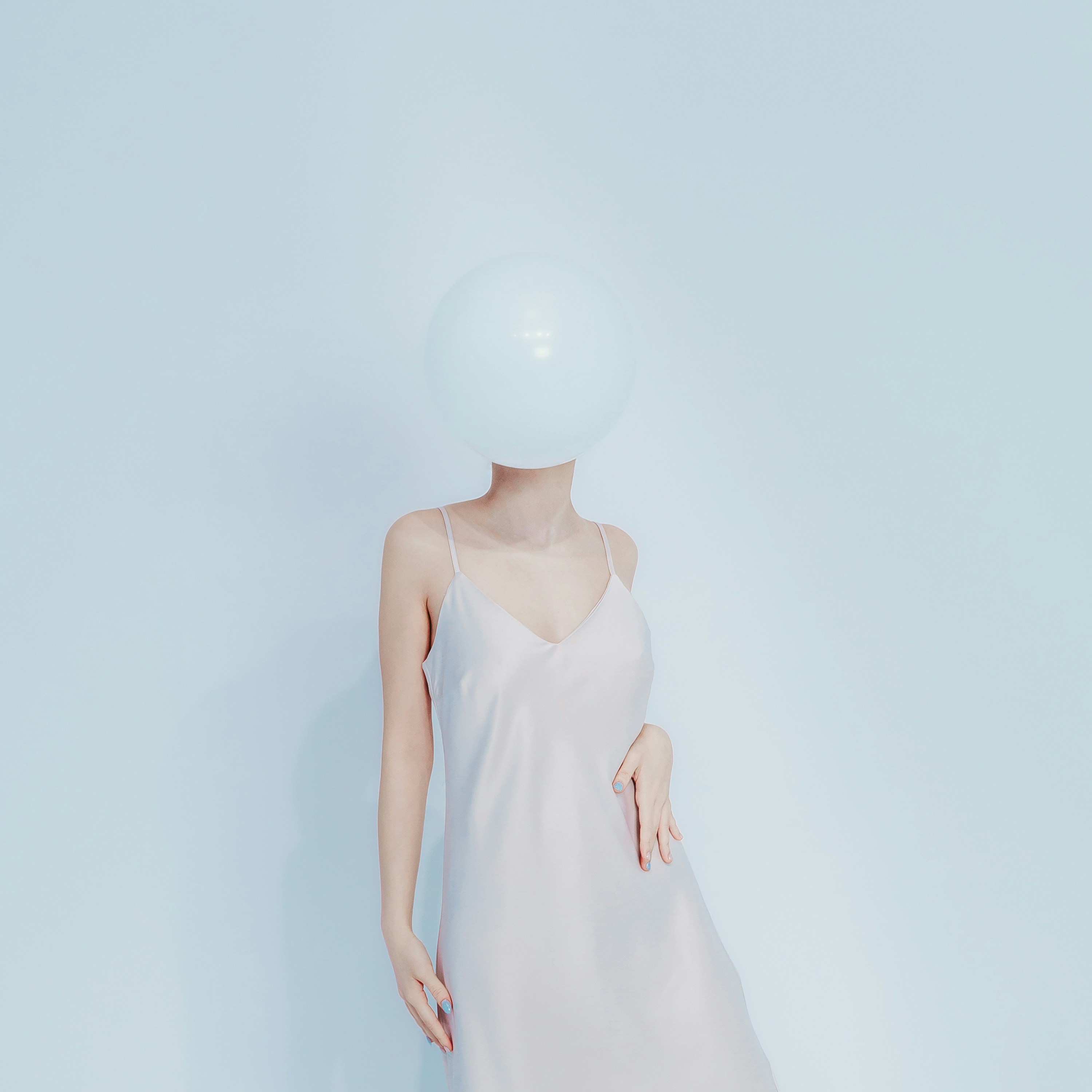 Woman in dress with balloon obscuring face