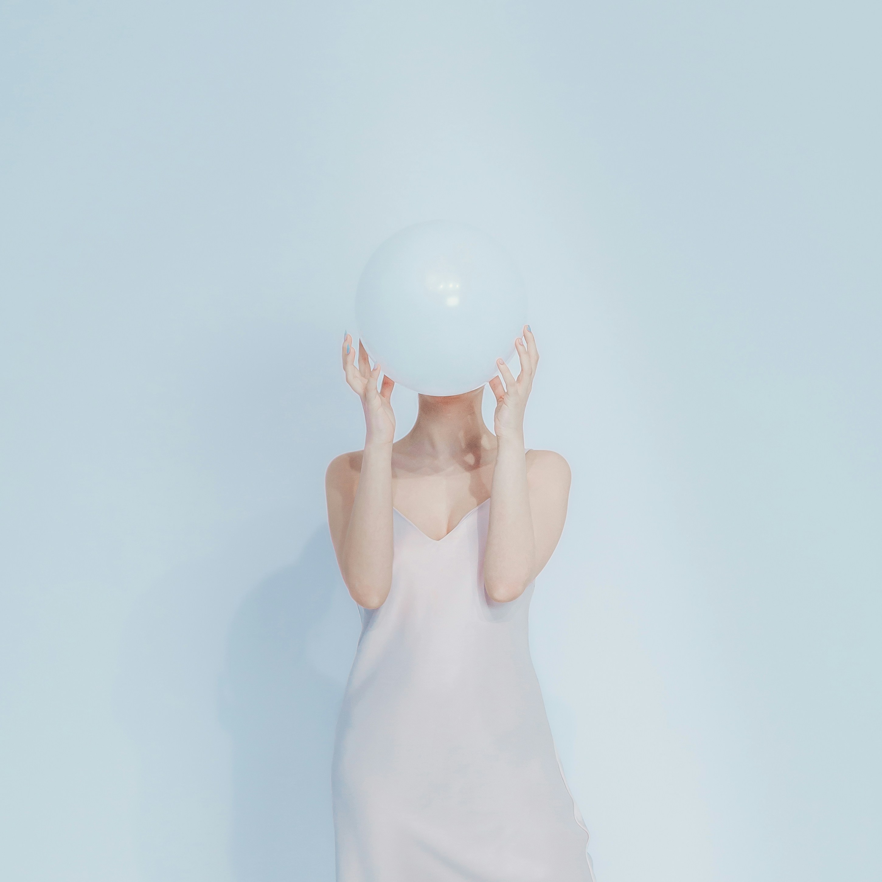 Woman holding a white balloon in front of her face.
