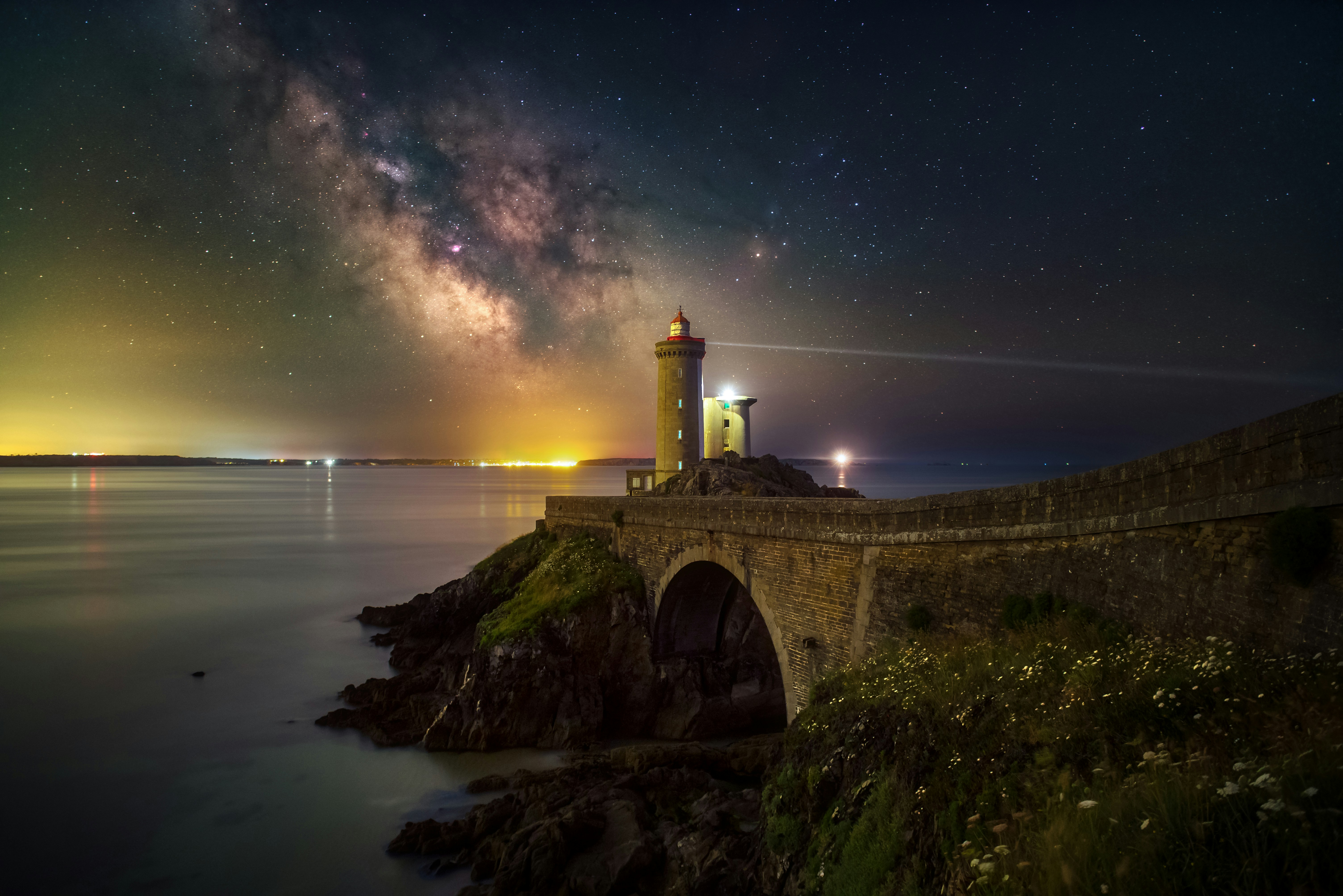 Lighthouse on a rocky coast under the milky way.
